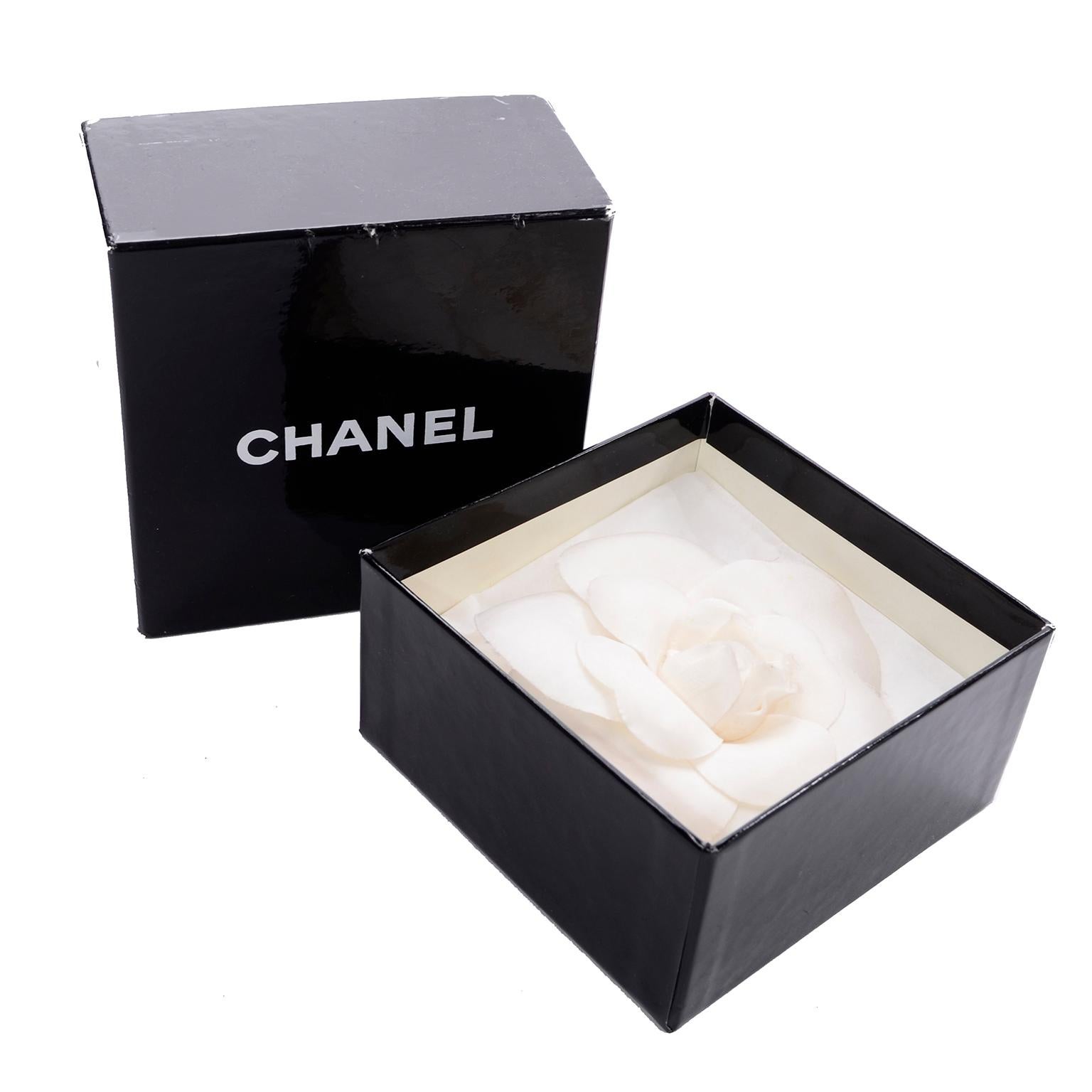 This is a collectible white Chanel Camellia Flower Pin with the Chanel gold tone plate: 