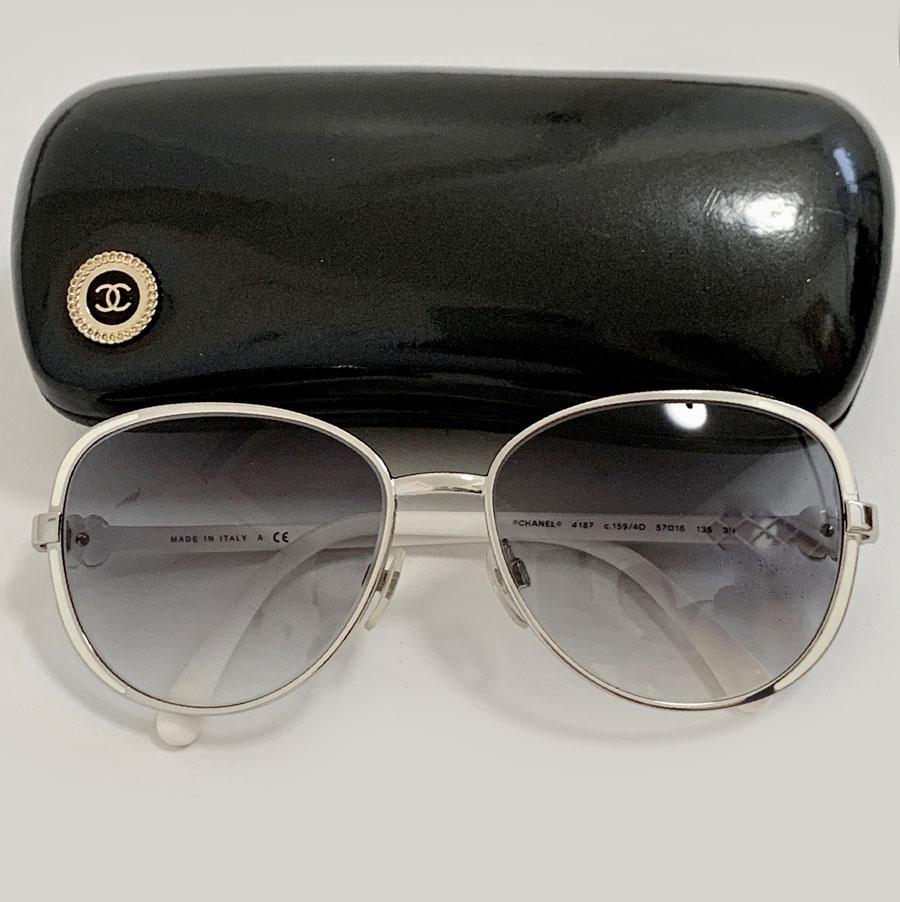 Elegant pair of Camélia CHANEL sunglasses in silver and white metal. A white camellia is on each branch (see photo). The glasses are in a gradient of blue.
The frame and the glasses are in good condition. A slight pink color is present on the
