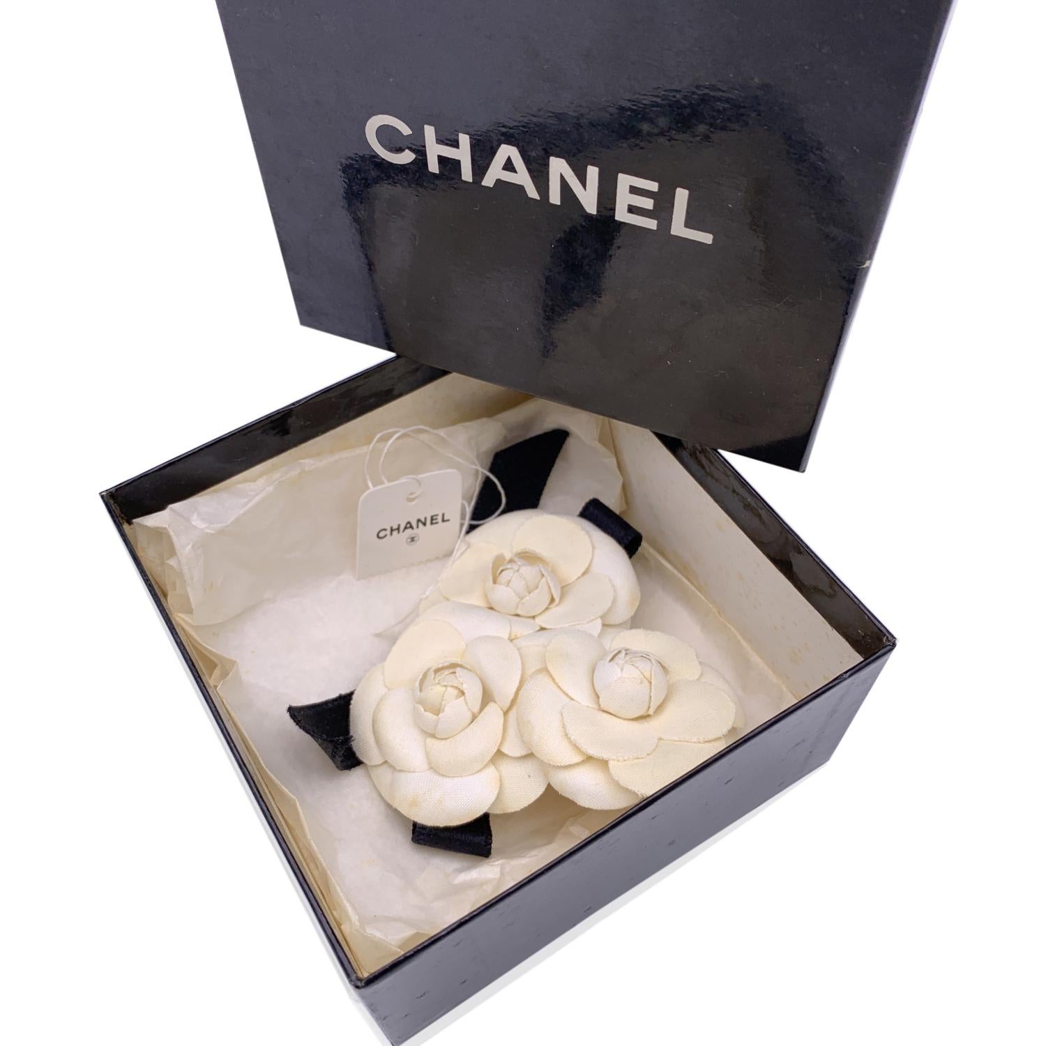 Chanel Vintage Triple Camelia Camellia Flower Pin Brooch. 3 white canvas flowers with black satin bow. Safety pin closure. Measurements (W x H): 4.5 x 3 inches - 11.5 x 7.6 cm. 'CHANEL - CC - Made in France' oval tab on the back

Condition

B - VERY