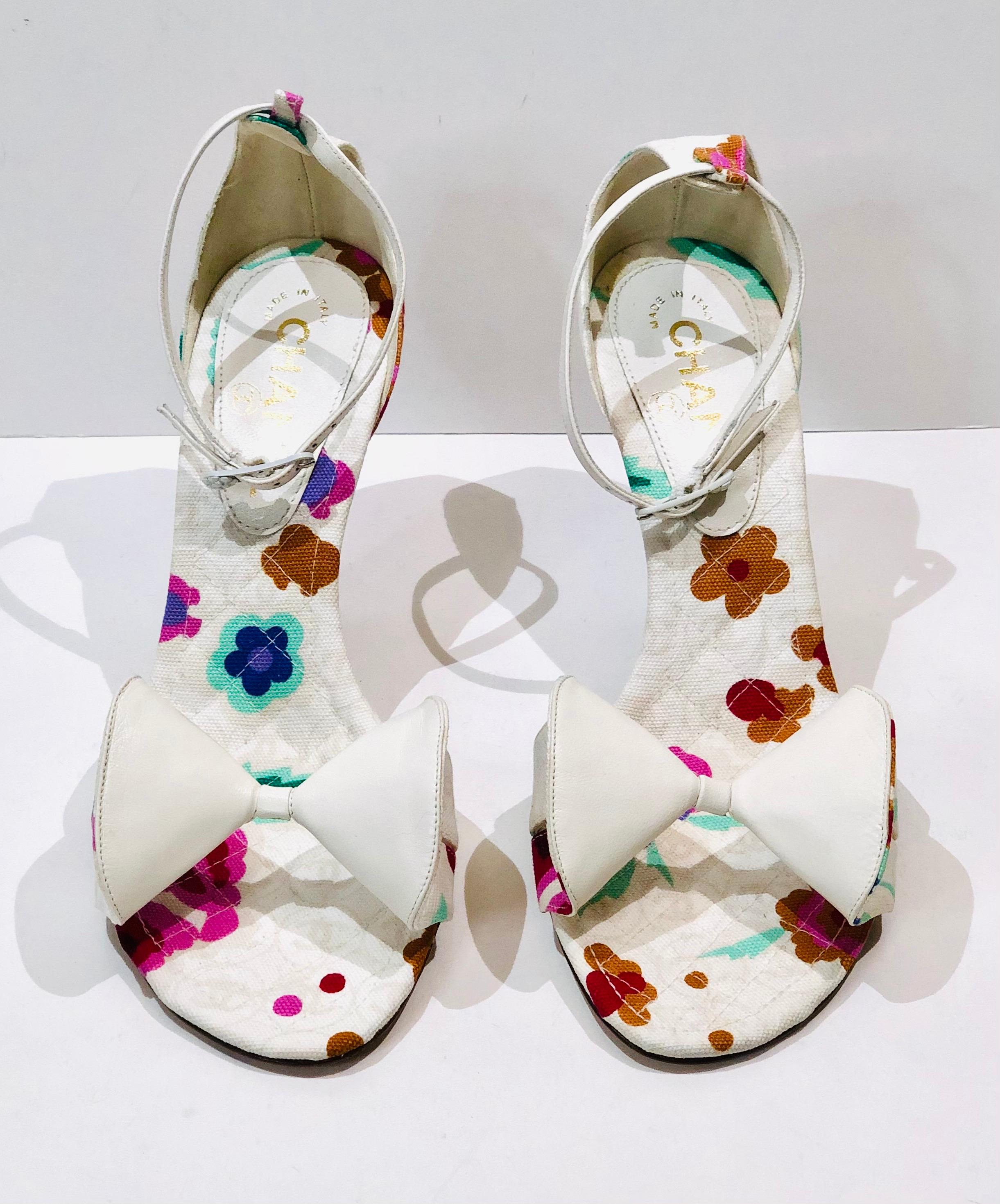 - Chanel white canvas floral print strap sandals in heels. 

- Leather white bows in front. 

- Flower hardware leather strap. 

- Size 38. 
