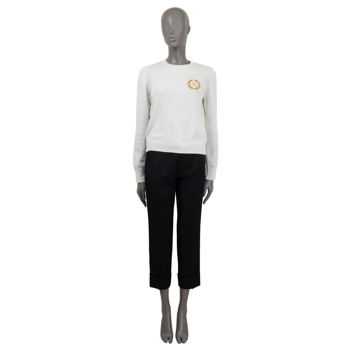 100% authentic Chanel 2020 Rue Cambone long sleeve sweater in off-white cashmere (97%), polyamide (2%) and polyurethane (1%). Features a gold and pearl embellished emblem on the chest. Unlined. Has been worn and is in excellent