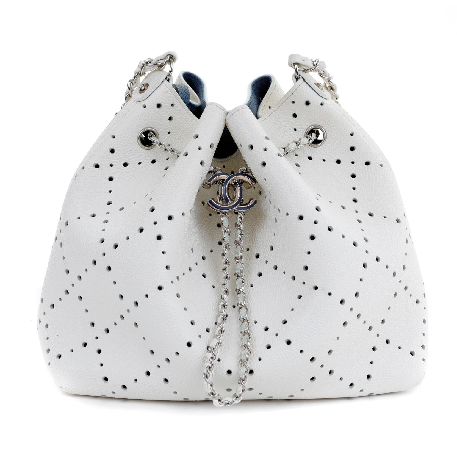 This authentic Chanel White Caviar Perforated Bucket Bag is in pristine condition.  Snowy white caviar leather is textured and durable.  Bucket bag silhouette in perforated diamond pattern allows glimpses of the blue interior. Silver and blue