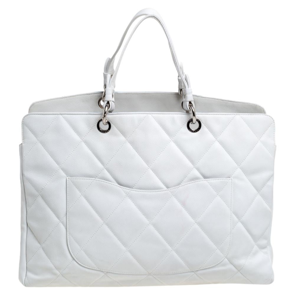 Give your wardrobe an instant elegant boost with this stunning Timeless tote from Chanel. It has been crafted from white caviar leather in the signature quilt design and features dual handles, silver-tone hardware detailing, and protective metal