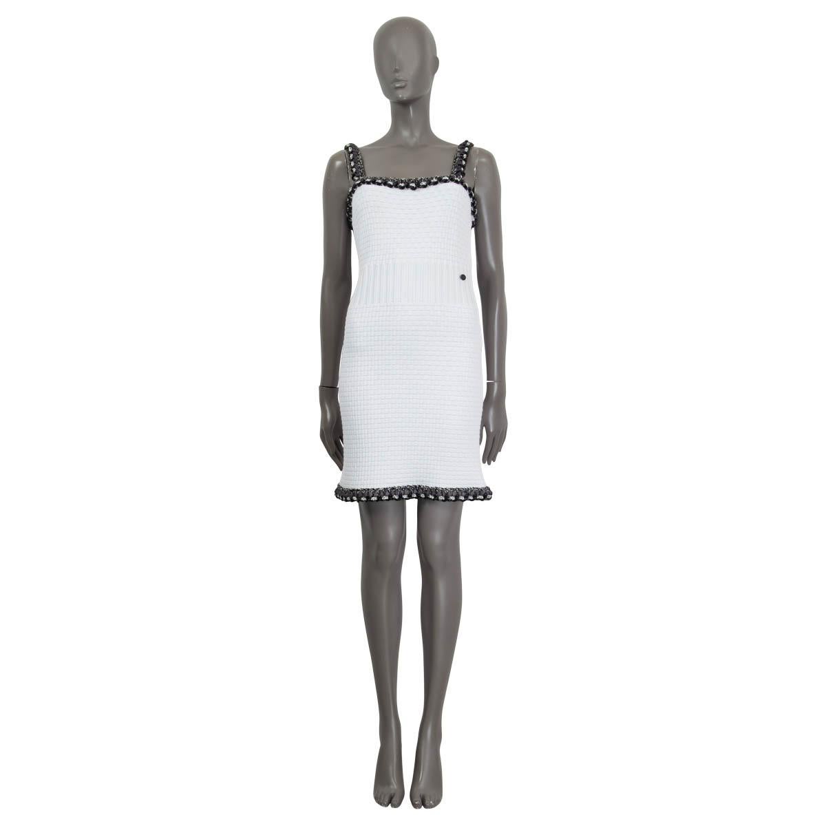 100% authentic Chanel Pre-Spring 2014 sleeveless knit dress in white rayon (44%), cotton (33%), nylon (11%), polyester (11%) and spandex (1%). Features a black chain embellished trim and a 'CC' emblem at the front. Opens with a concealed zipper and