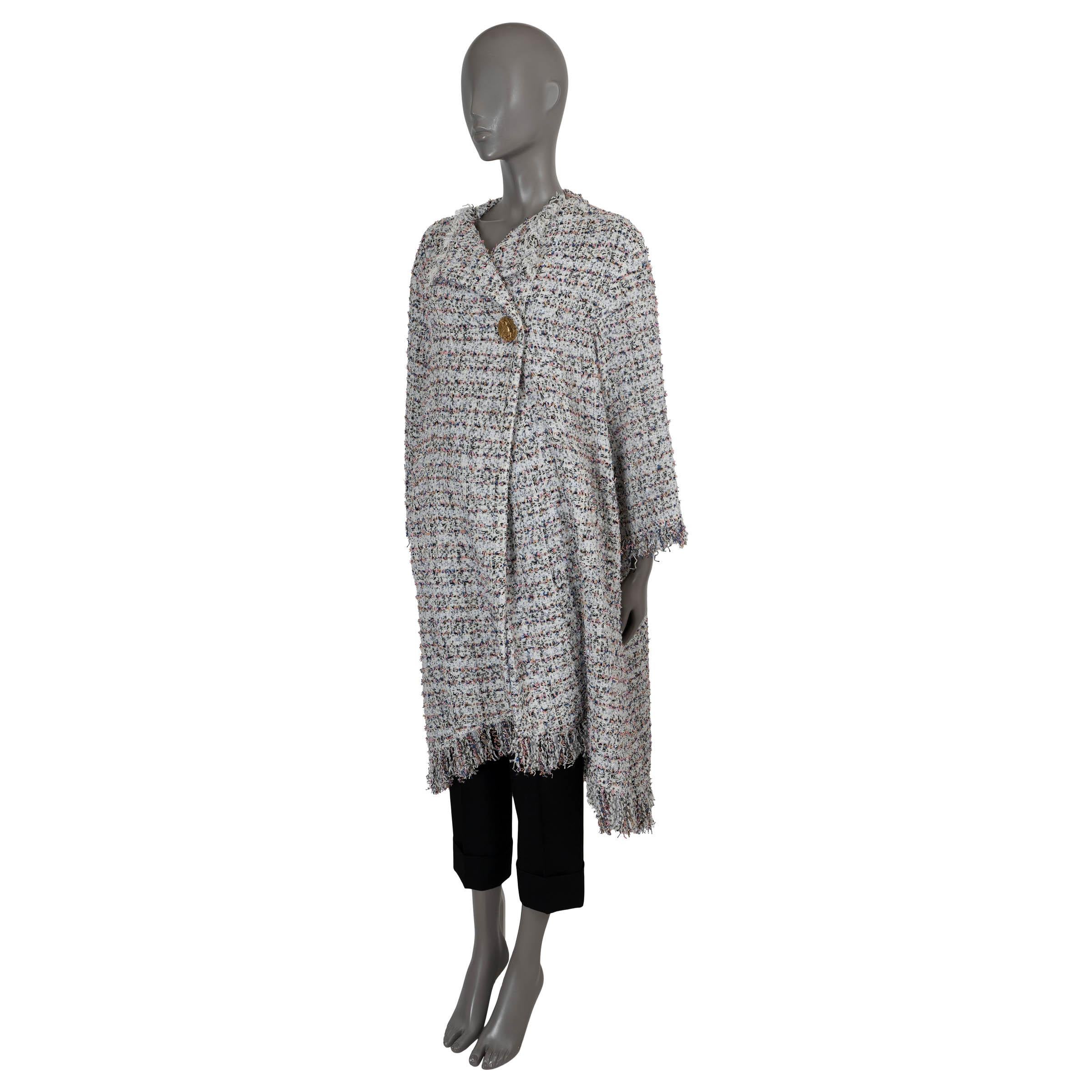 100% autentico cappotto Chanel in tweed di cotone bianco, rosa, blu e marrone (100%). Presenta una silhouette oversize e rilassata, maniche a 3/4, bordi con frange e due tasche a filetto in vita. Si chiude con un bottone a forma di moneta di cavallo