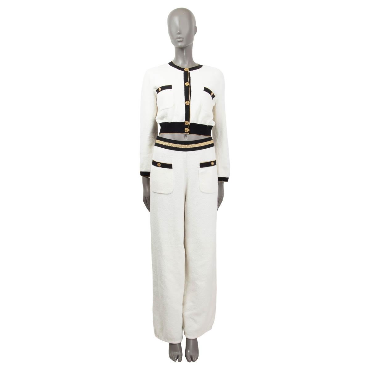 100% authentic Chanel cropped terrycloth knit cardigan in white cotton (83%) and polyamide (17%). The design features black elastic rib bands with a gold-tone lurex trim and two buttoned patch chest pockets. Embellished with gold-tone metal logo