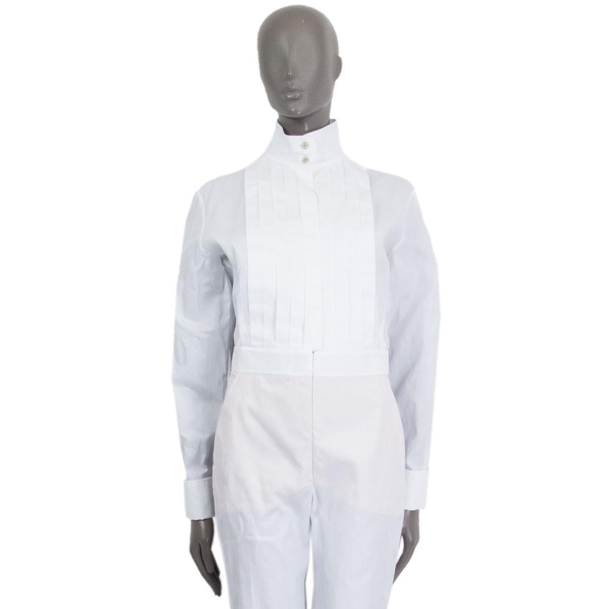 100% autentica tuta aderente Chanel in cotone bianco (100%) con piega frontale, colletto a fascia, due tasche laterali, pantaloncini al ginocchio foderati in un intimo color tan. Si chiude sul davanti con un bottone e una cerniera nascosta. Nuovo di