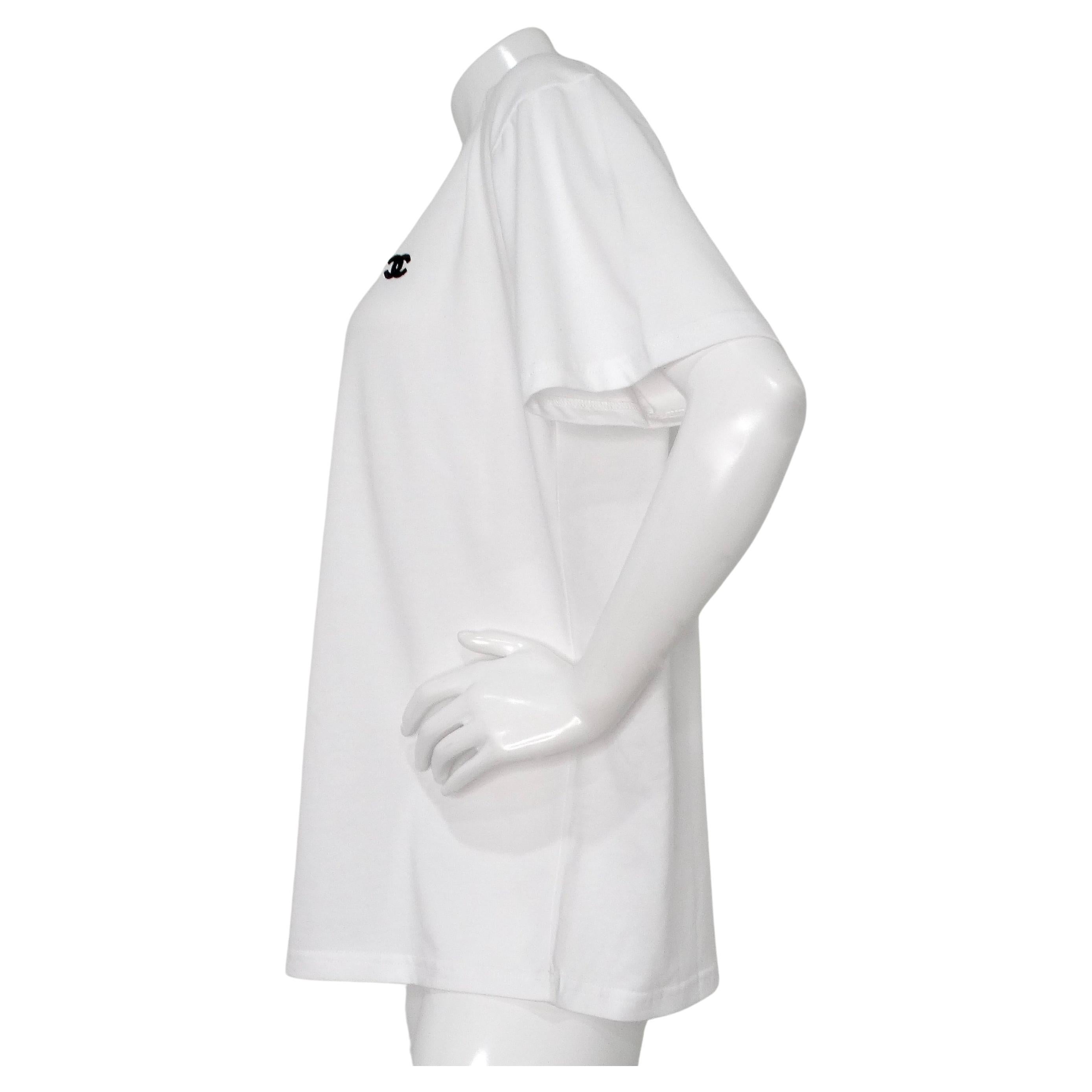 The Chanel White Cotton Interlocking CC Embroidered Logo Uniform T-Shirt is a sophisticated and versatile piece designed for those who appreciate understated luxury. Crafted from crisp white cotton, this uniform T-shirt features the iconic