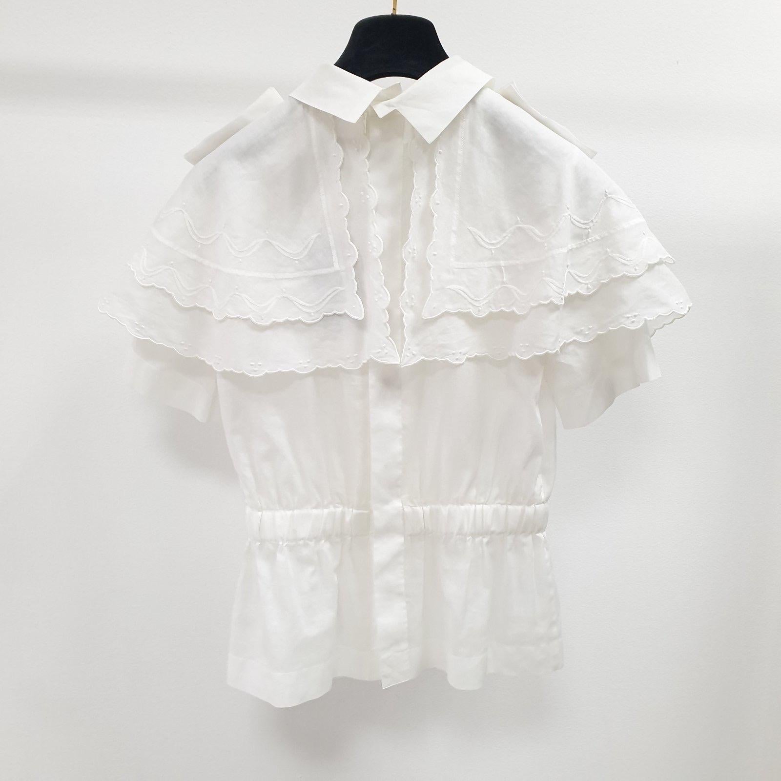 The house of Chanel brings to you this luxuriously detailed top that can be flaunted for a stylish look of grace. 
Crafted from cotton that is enhanced with scalloped overlays and camellia motifs on the epaulets, this top can easily be worn with