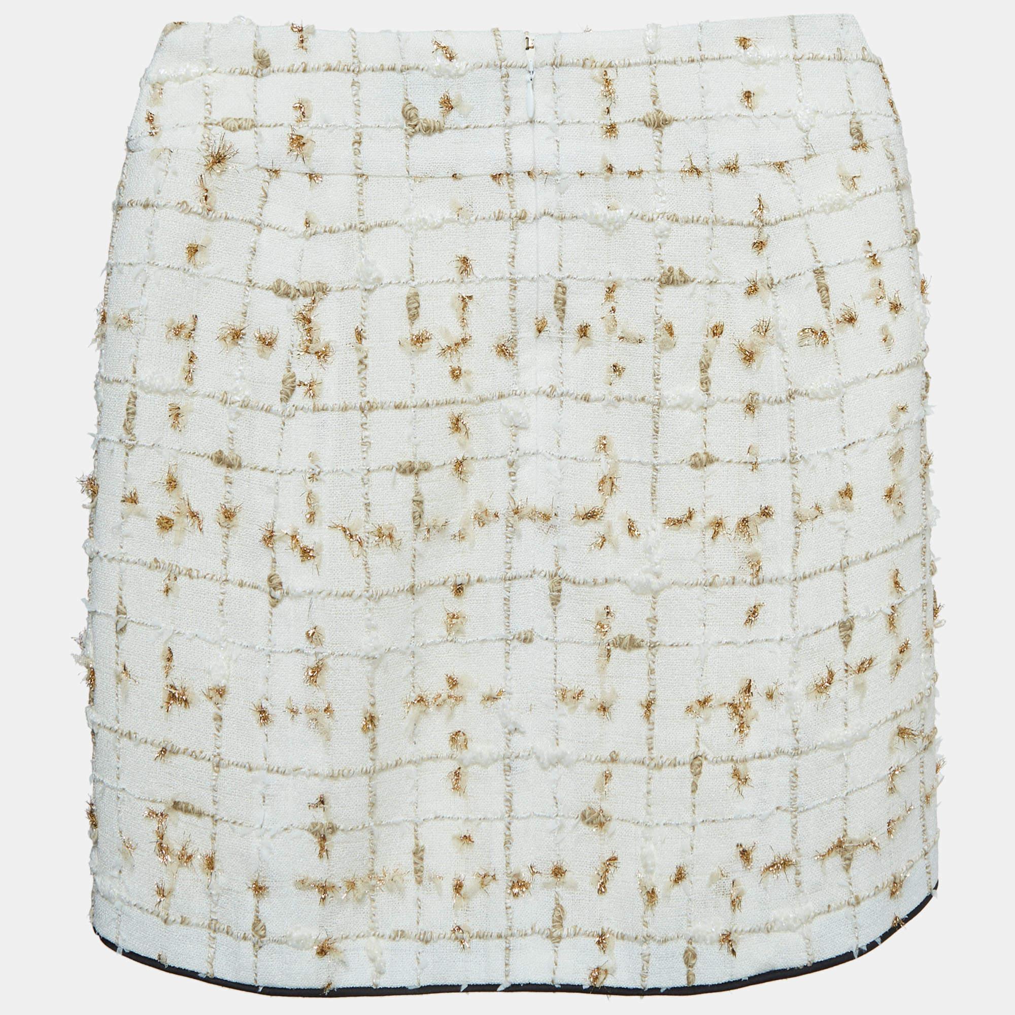 Indulge in timeless elegance with the Chanel tweed skirt. Crafted with meticulous attention to detail, this exquisite piece features a sophisticated blend of white and gold hues, woven into a classic tweed pattern, exuding sophistication and charm.

