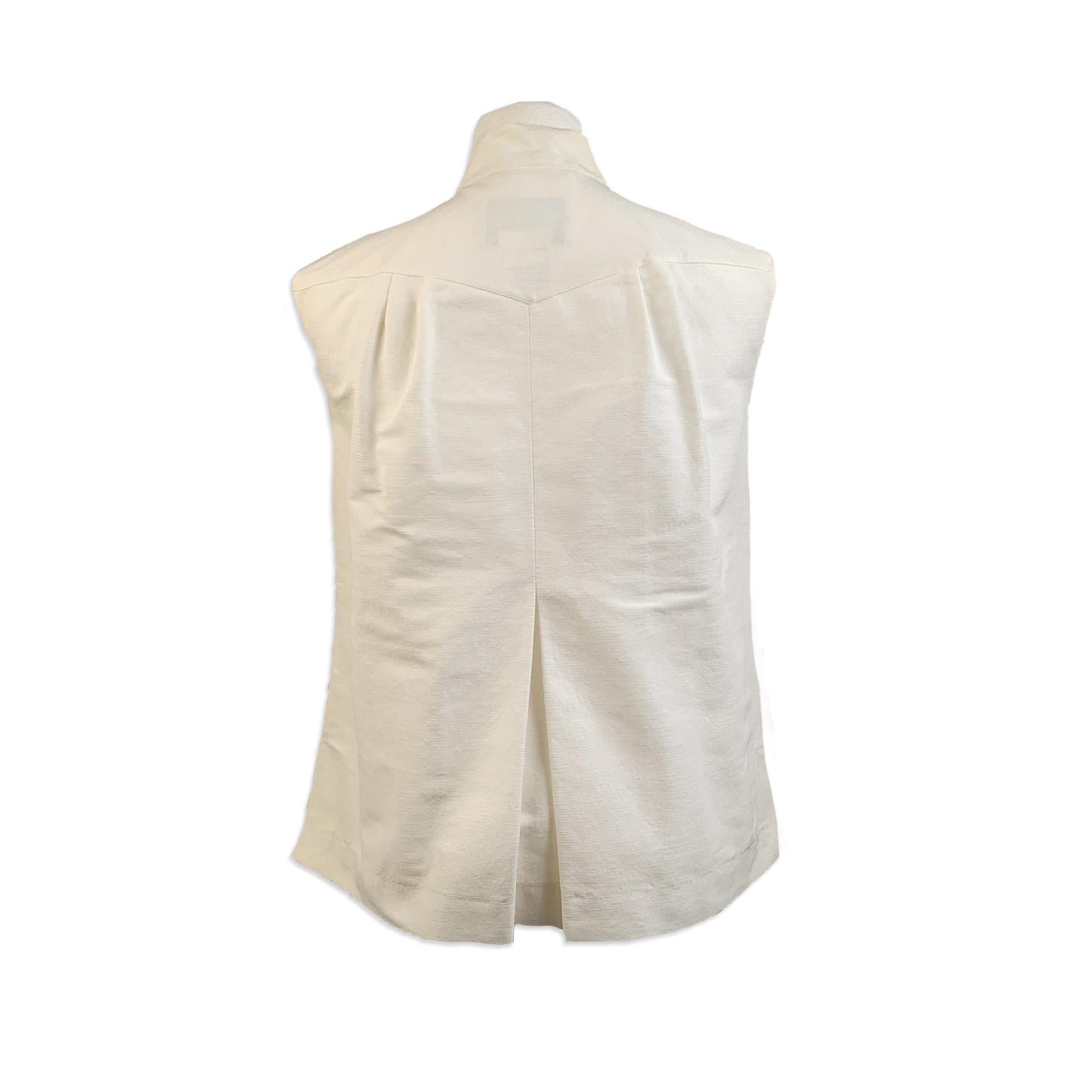 Chanel white grosgrain vest/sleeveless top. The vest features sleeveless styling, a button closure on the front, bow detail on the neckline and pleating detailing. 2 flap pockets on the chest. Unlined. Composition: 62 % Cotton, 26% Nylon, 9 %