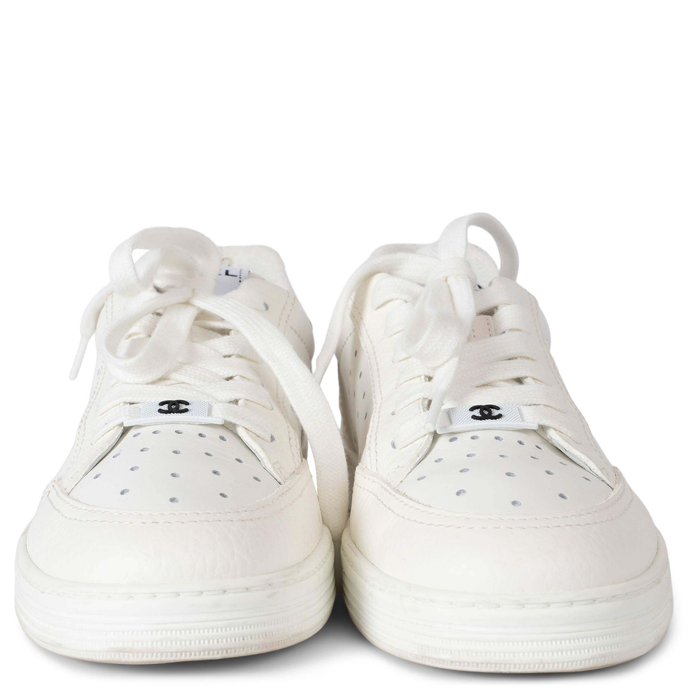 These 100% authentic Chanel low-top sneakers are crafted from white perforated leather, offering a sleek, minimalist design. They feature grained leather trim with logo embossing on the heels, adding a subtle yet distinctive touch. Finished with