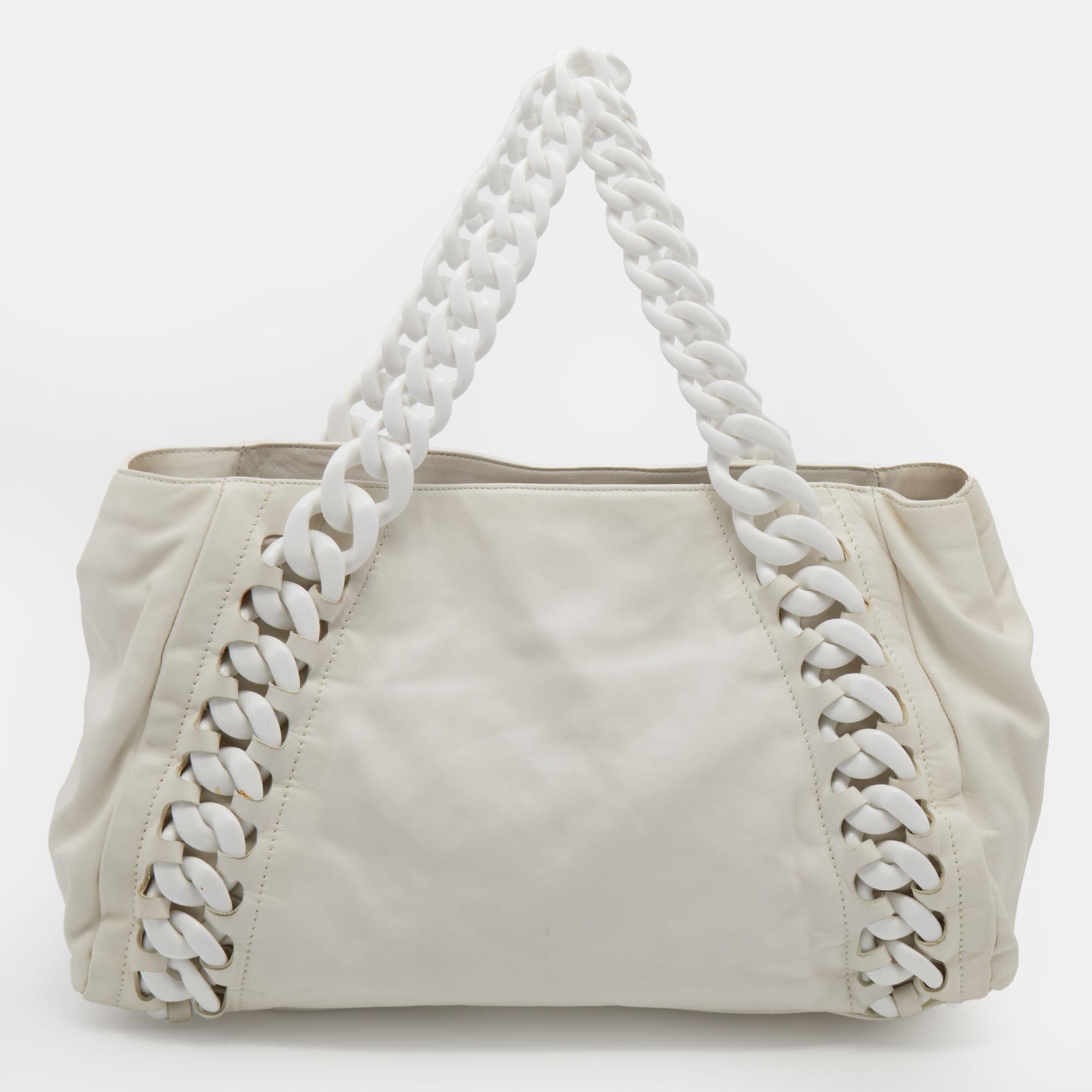 The Chanel tote is ideal for those who commute daily, love shopping, and travel often. Made from white leather, the creation is highlighted with a CC front logo and attached with chain trims. The spacious interior makes it a fashion-meets-function