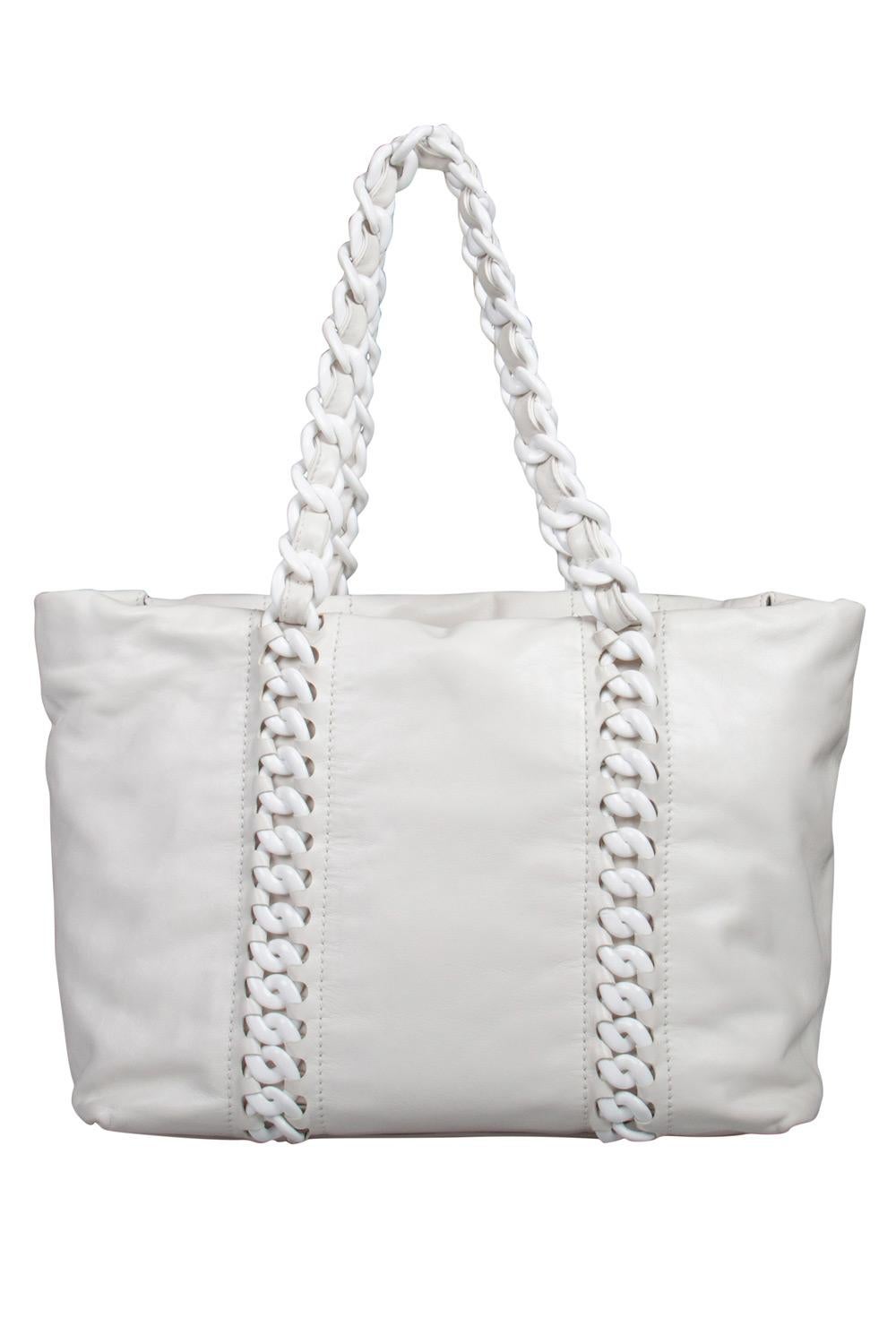 The Rhodoid tote combines classic Chanel with edgy detailing, creating a unique, modern day bag. Its all white leather exterior with the large CC logo is accented with bold chain link handles. The spacious interior is lined with satin and features
