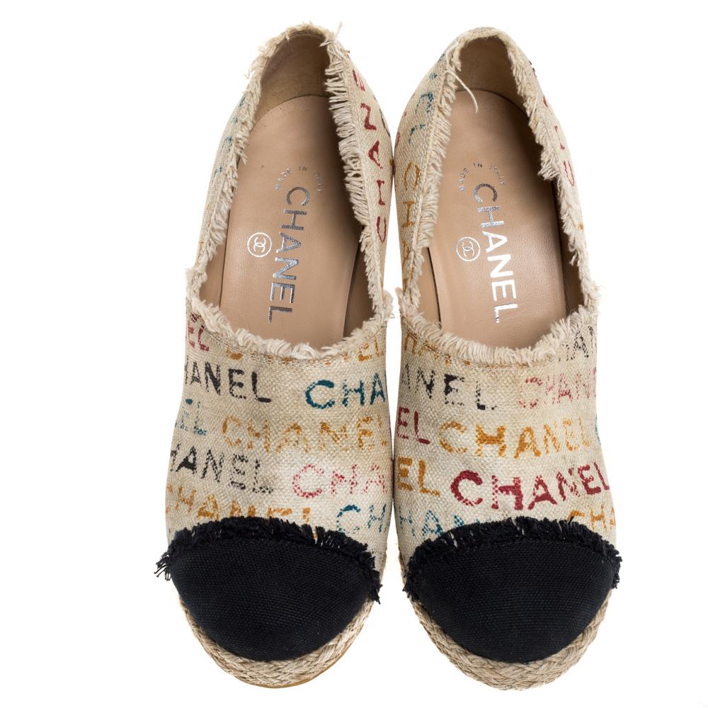 Deliver a signature look with these Chanel espadrille clogs. Crafted meticulously from logo printed canvas, they come in a lovely shade of white that is contrasted with black cap toes. They are styled with low platforms, 12 cm heels, silver-tone