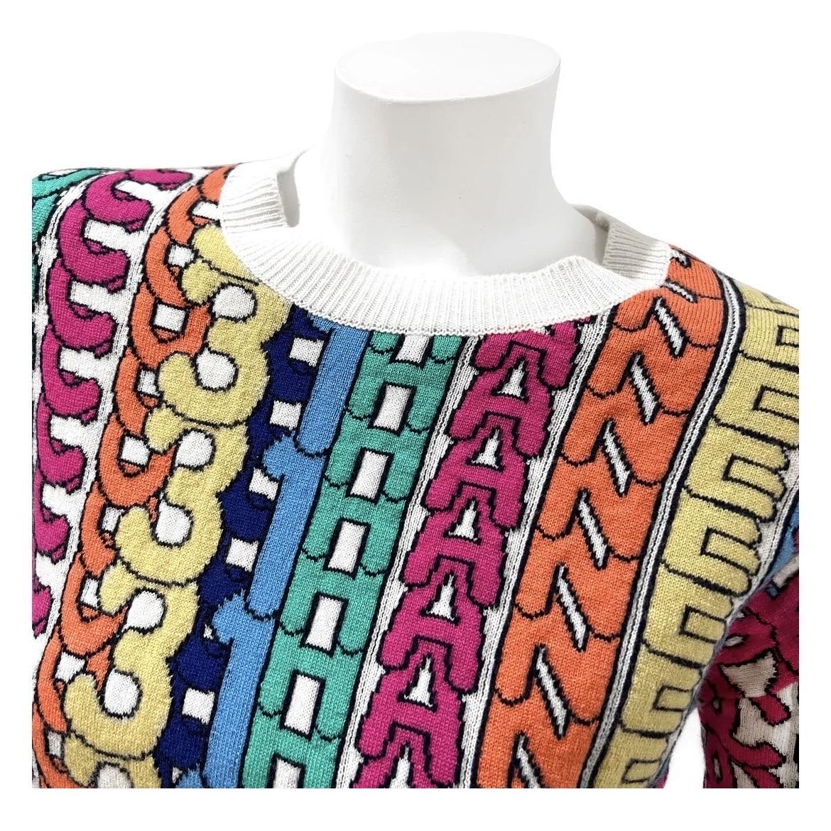 White Multicolor Cashmere Logo Print Intarsia Sweater by Chanel 
Fall 2021
Made in U.K.
White with multicolor 'Coco Chanel' logo print detail
Ribbed white collar, bottom and cuffs
Long sleeve
Slip-on
Knit material 
Crew neck 
Square silver 'CC' logo