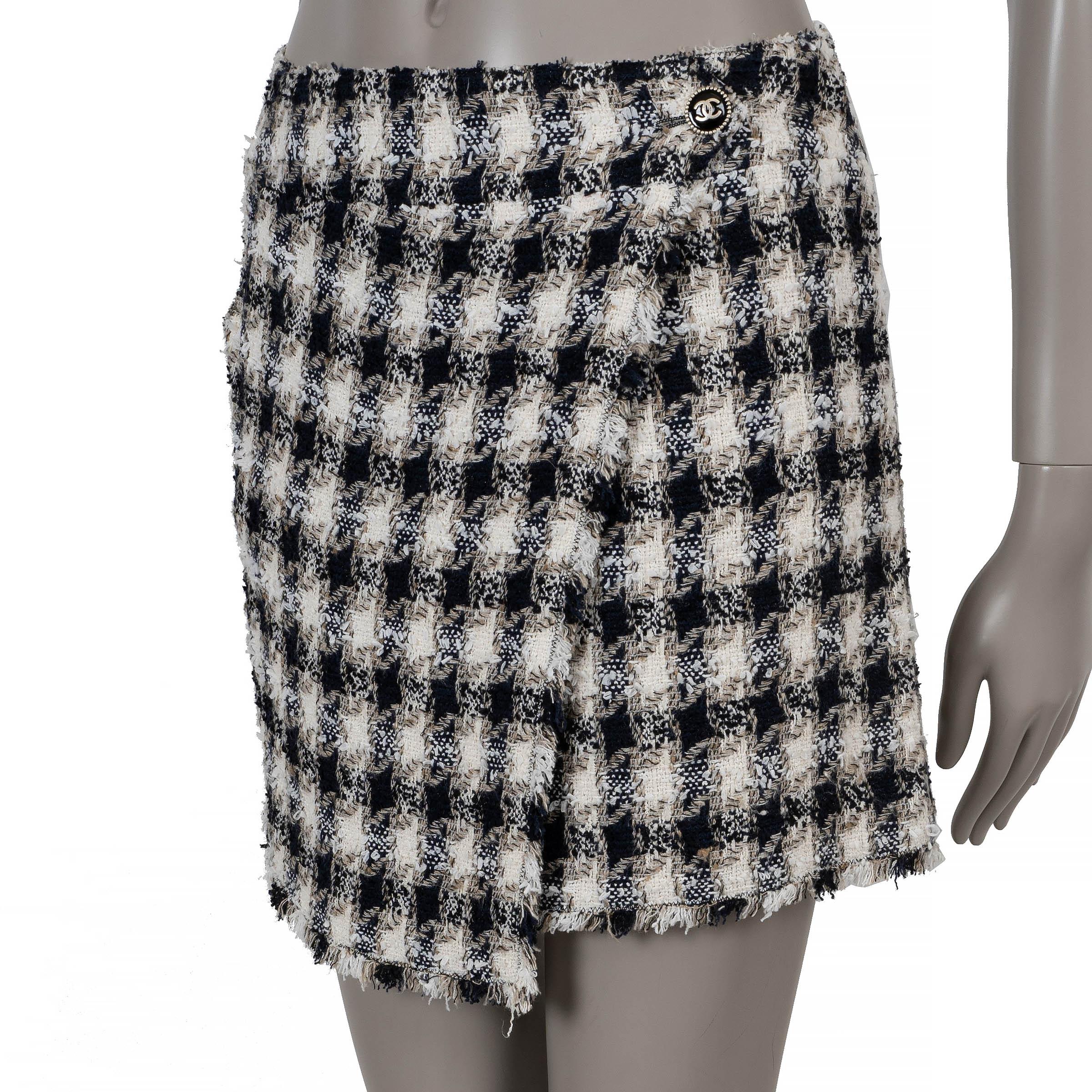 Questa gonna Chanel 100% autentica in tweed a quadri neri, bianchi e beige in cotone (53%), rayon (21%), nylon (12%), seta (9%) e poliestere (5%) unisce motivi classici a una sartoria moderna. Caratterizzata da una silhouette mini asimmetrica,