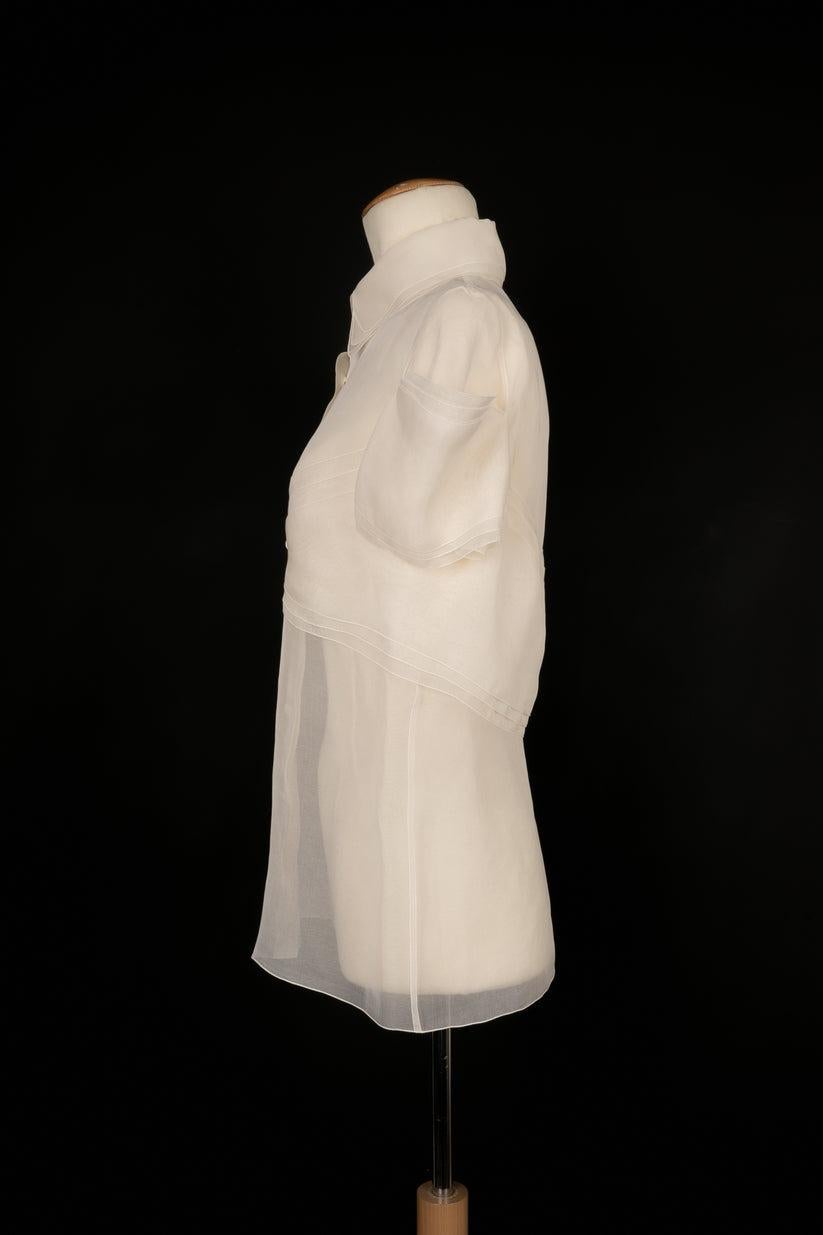 CHANEL - White organza blouse with short transparent sleeves and cc buttons. No size indicated, it fits a 36FR/38FR. Brand label missing.

Additional information:
Condition: Good condition
Dimensions: Shoulder width: 38 cm - Chest: 44 cm - Sleeve