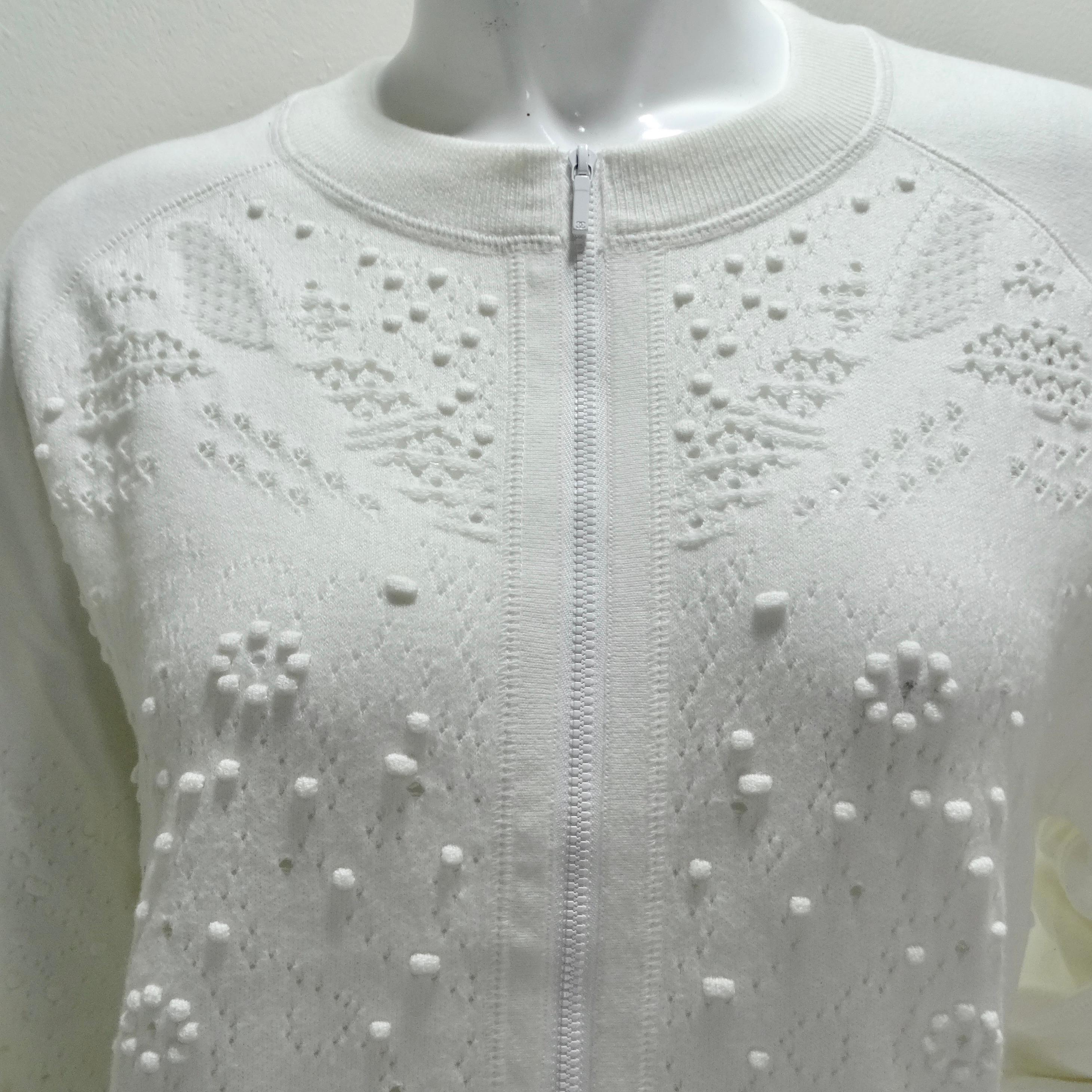 Der Chanel White Perforated Knit Zip Up Sweater ist ein luxuriöses und vielseitiges Modell, das Komfort und die für Chanel typische Eleganz nahtlos miteinander verbindet. Dieser klassische Pullover mit Rundhalsausschnitt und Reißverschluss ist aus