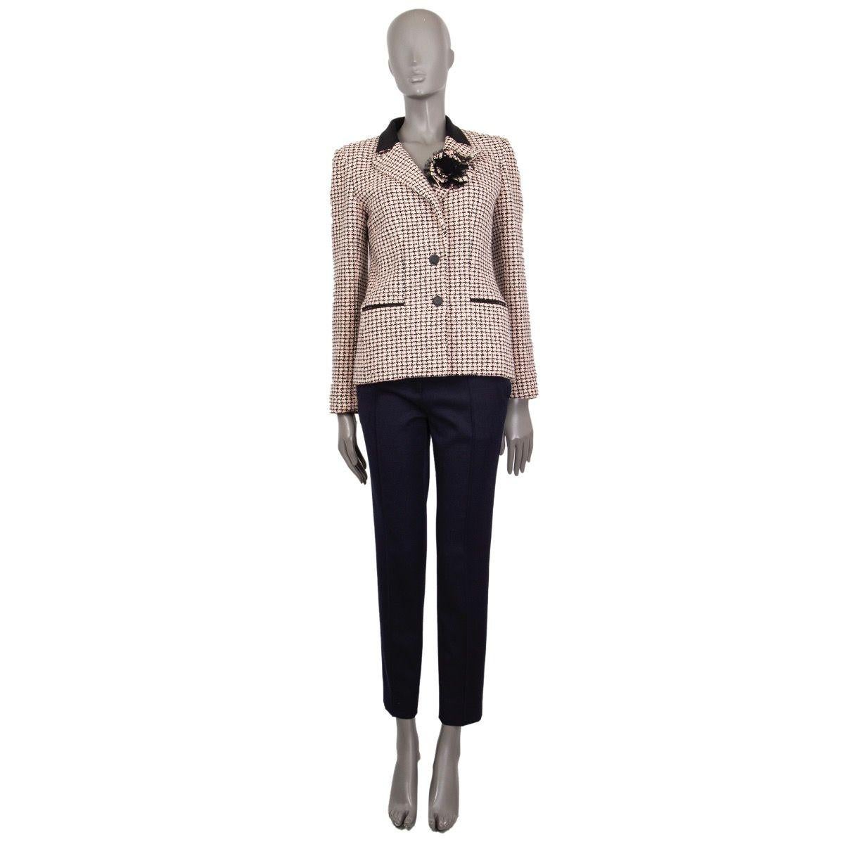 Chanel houndstooth tweed blazer in black, off-white and rose cotton (100%) with a notch collar, flower-brooch and two slit pockets. Closes on the front with buttons. Cuffs fasten with buttons. Lined in silk (100%). Has been worn with some wear on