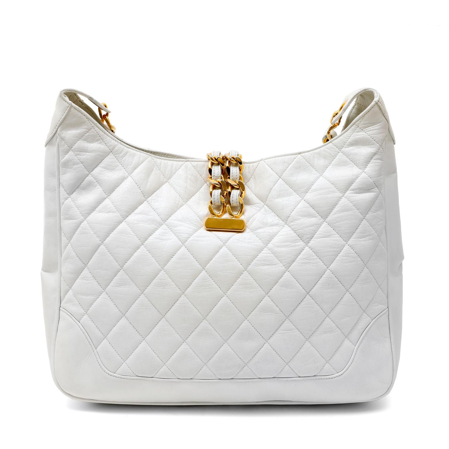 This authentic Chanel White Quilted Leather Structured Hobo is an early vintage piece in beautiful condition.  Rare and collectible; a unique style not often seen.  
Snowy white leather is quilted in signature Chanel diamond pattern.  Double leather
