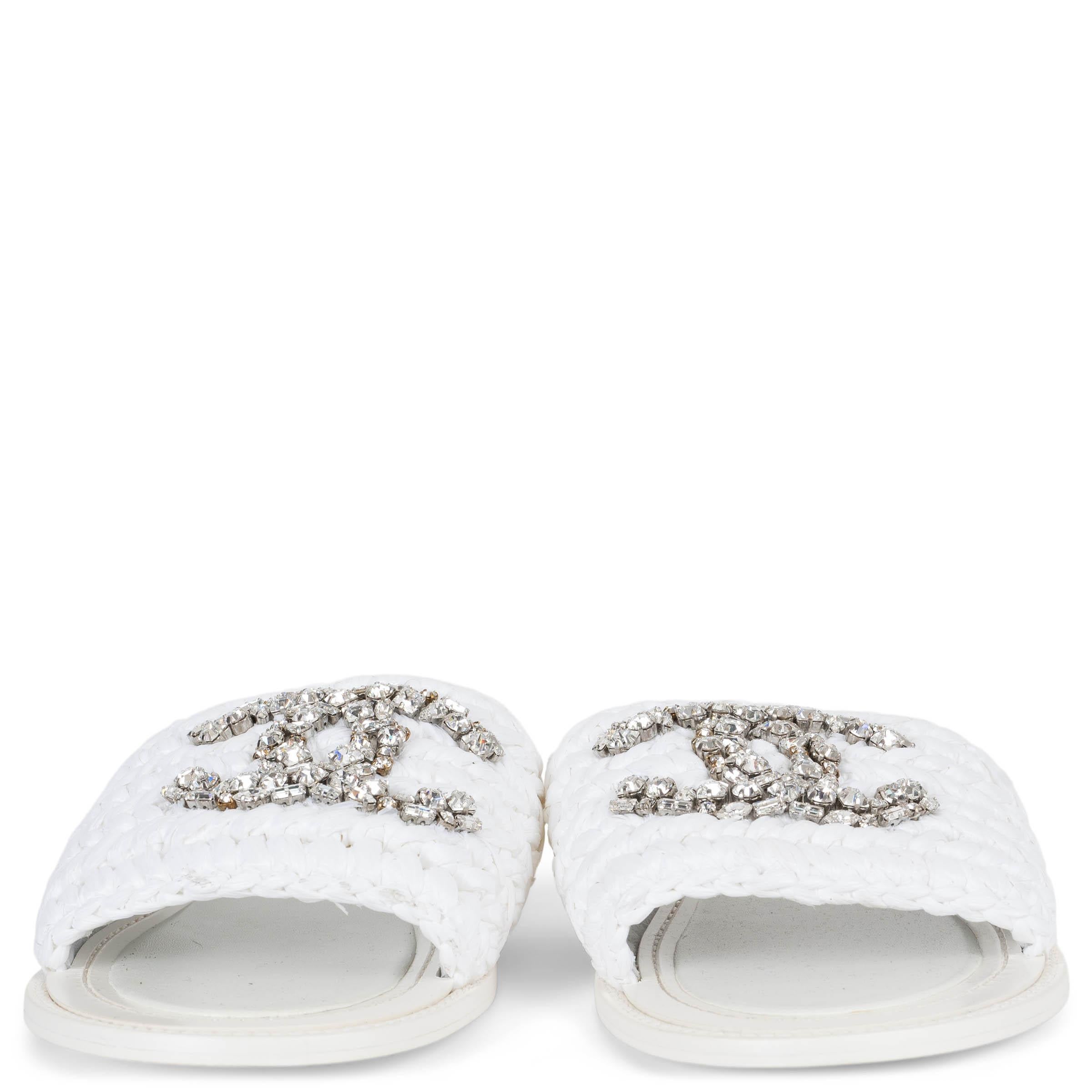 Ces diapositives 100 % authentiques de Chanel sont confectionnées en raphia tissé blanc et ornées d'un logo CC en cristal étincelant sur le devant. Dotées d'un bout arrondi et d'une semelle en cuir lisse, elles offrent une finition chic et sans