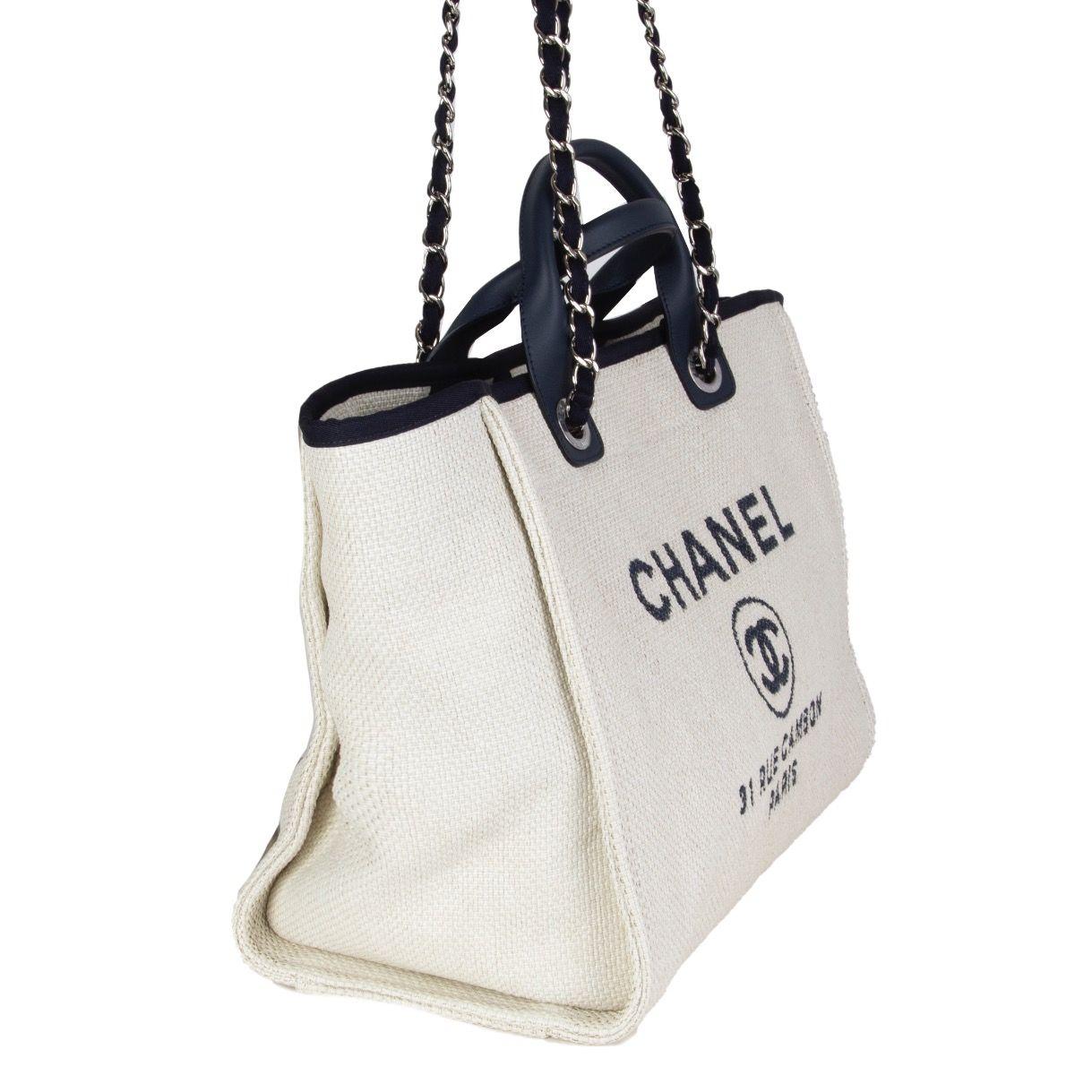 Chanel 'Deauville Large' shopper in white raffia and navy blue leather. Closes with a magnetic-snap on top. Lined in dark blue cotton with two open pockets against the front and a zipper pocket against the back. Has been carried and is in excellent