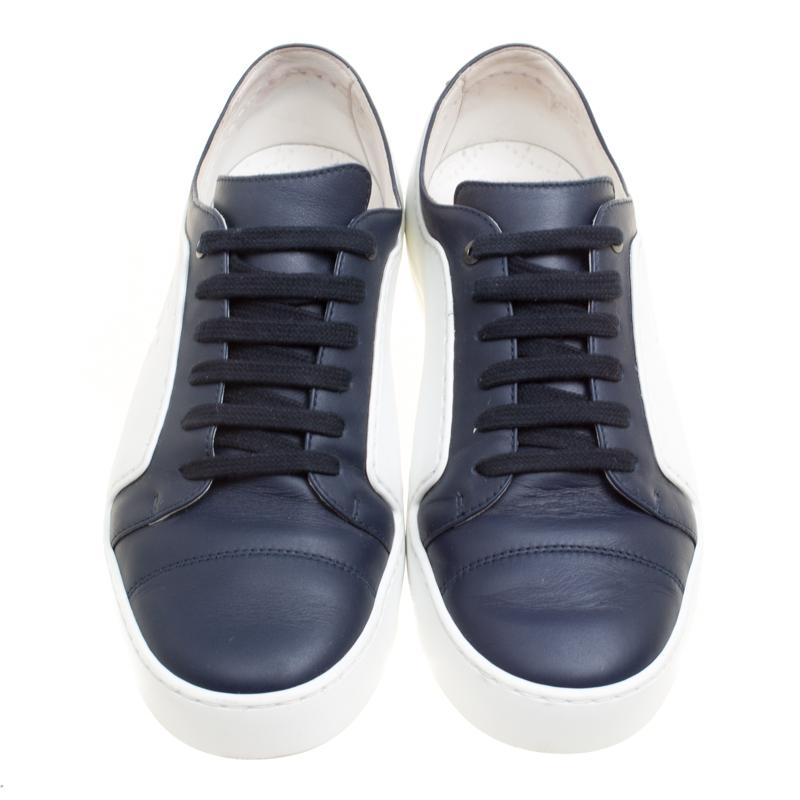 These fabulous low top sneakers from Chanel have the power to become your most loved pair of shoes! They are crafted from white rubber and navy blue leather and feature round toes and lace-ups on the vamps. They flaunt the signature CC logo