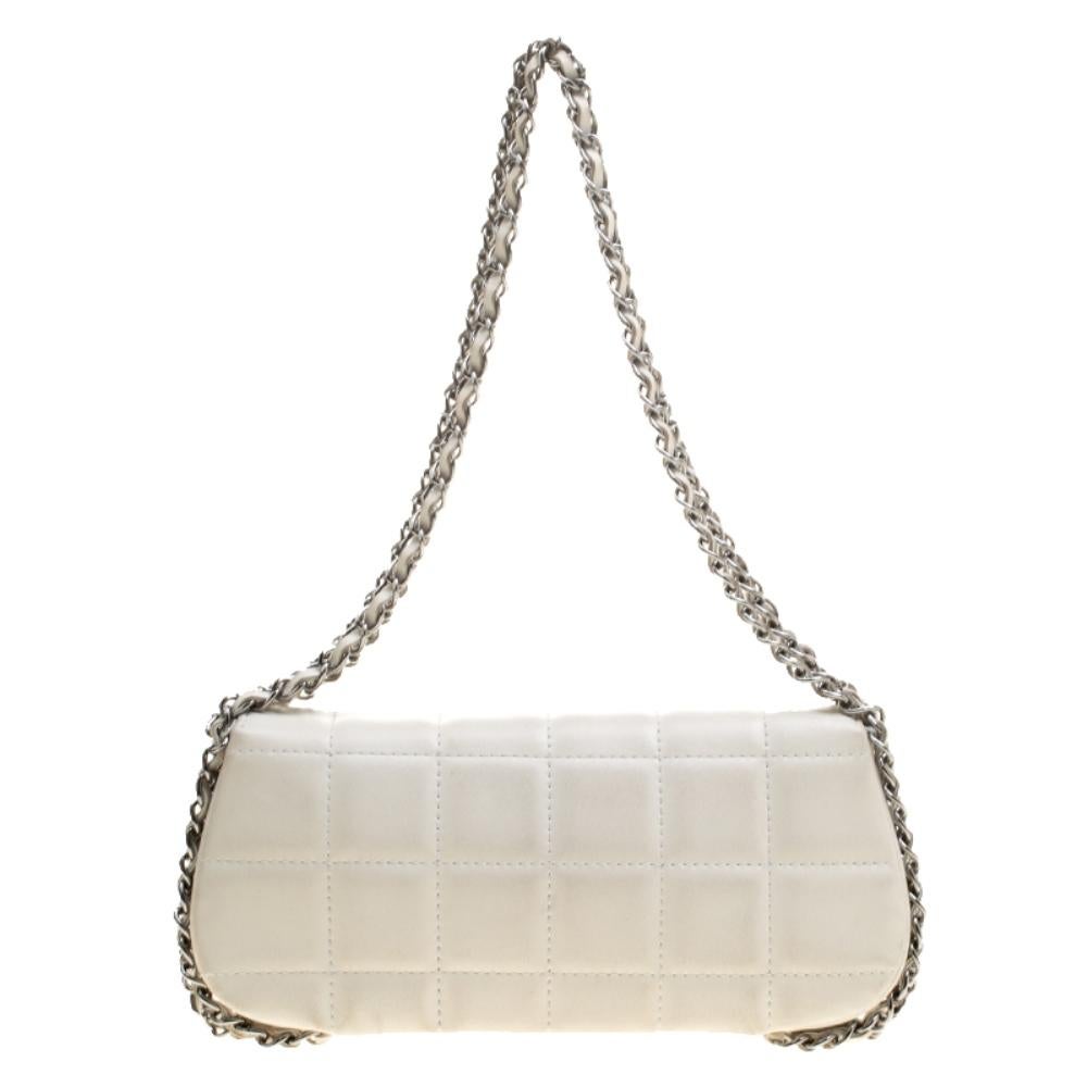 Famous as the little sister of Chanel's classic flap bags, this East West Baguette Flap Bag is a petite beauty with an understated charm and winsome appeal. The quilted style has been tweaked a little, a square pattern as against the signature