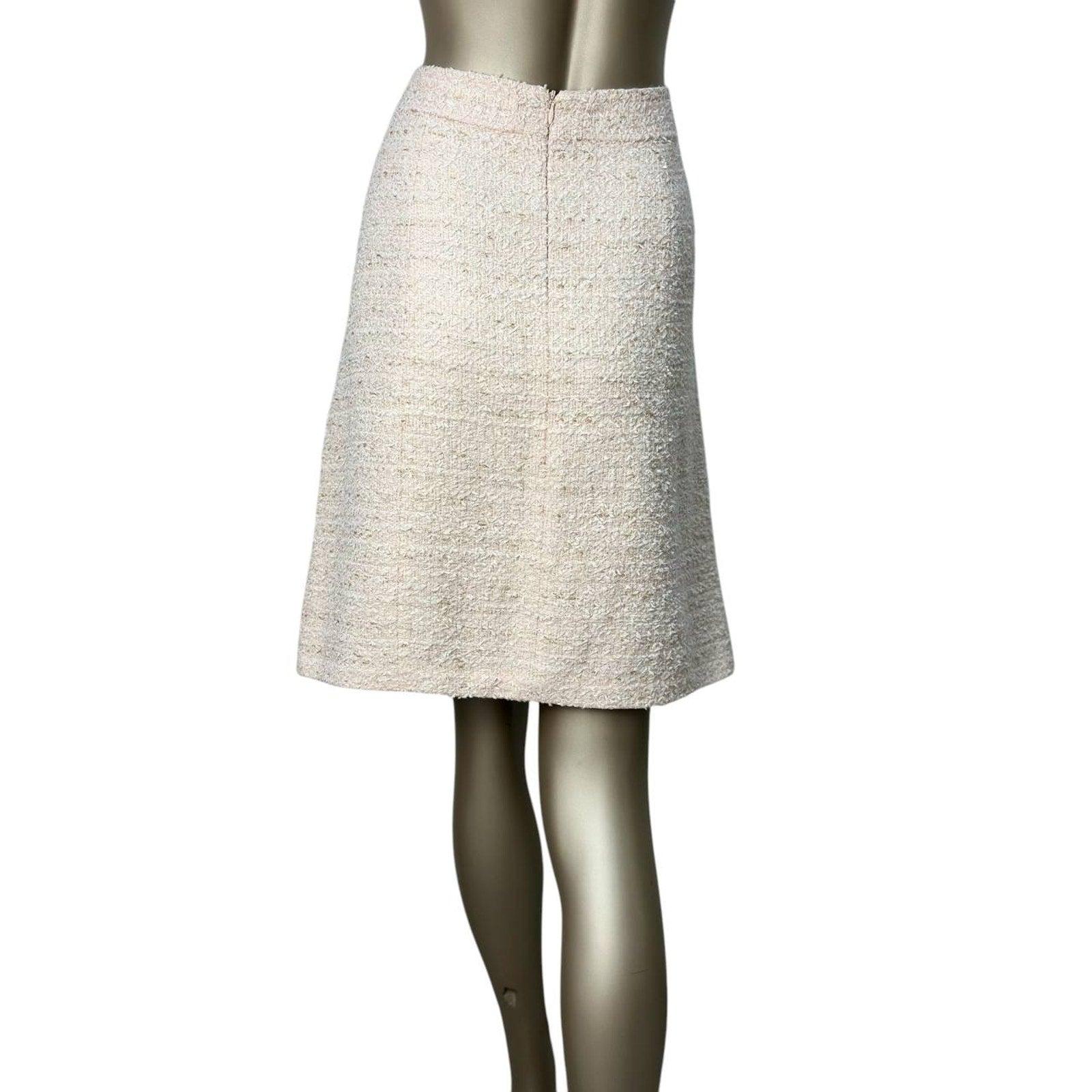 Rehaussez votre garde-robe avec cette superbe jupe en tweed blanc de Chanel. Cette jupe chic à coupe droite est confectionnée dans un luxueux tweed multifibre aux douces nuances ivoire-beige. 

Il est orné d'accessoires en métal doré, qui ajoutent