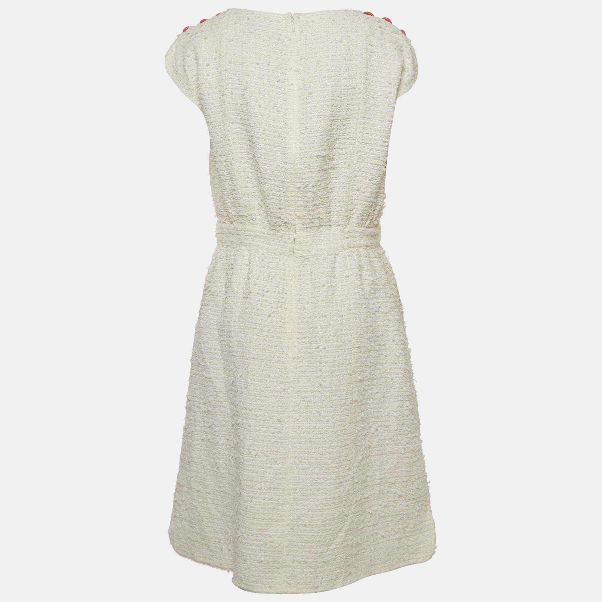 Chanel's white tweed sleeveless knee-length dress embodies timeless elegance. The luxurious fabric boasts a subtle texture, while the classic silhouette showcases the brand's signature sophistication. A perfect balance of refinement and modernity,