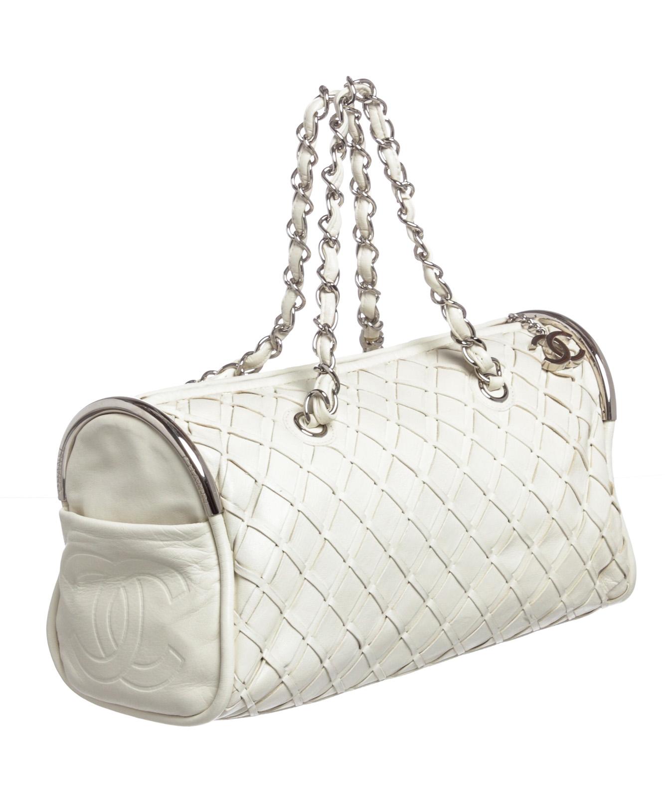 White woven leather Chanel Ultimate Soft Sombrero Bowler bag with silver-tone hardware, dual chain-link and leather shoulder straps, dual exterior slit pockets at sides featuring debossed CC logo accents, protective feet at base, creme satin lining,
