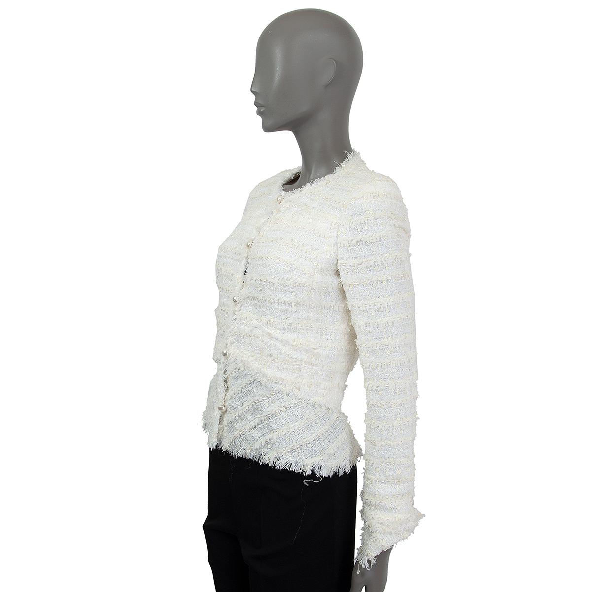 Chaqueta Chanel de bouclé embellecida con lentejuelas, de viscosa blanca y hueso (40%), algodón (20%), nailon (15%), poliéster (15%) y seda (10%), con hombreras, dos bolsillos decorativos delanteros y puños abotonados. Se cierra por delante con