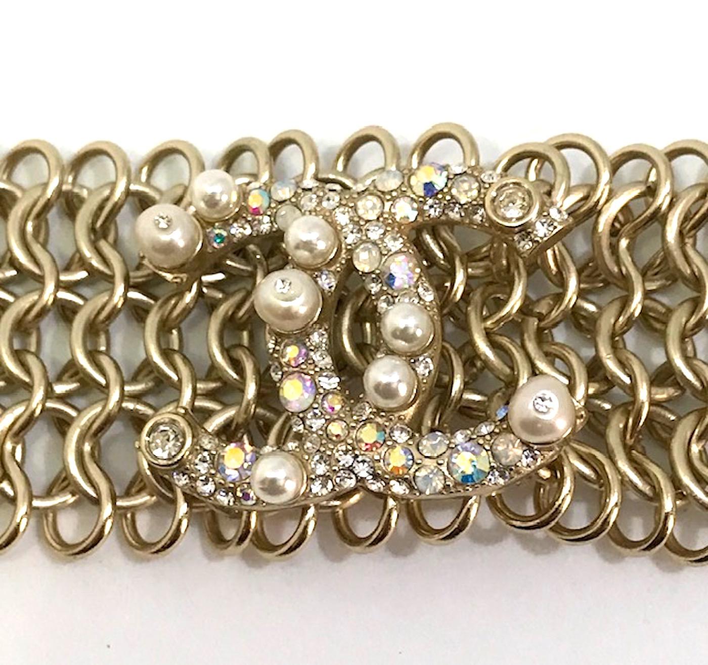 A wonderful Chanel wide gold tone chain link bracelet from the Autumn 2018 collection. The large iconic interlocking Chanel CC logo is incrusted with faux pearls and iridescent rhinestones. the bracelet measures 1.5 inches wide and 9.75 inches long