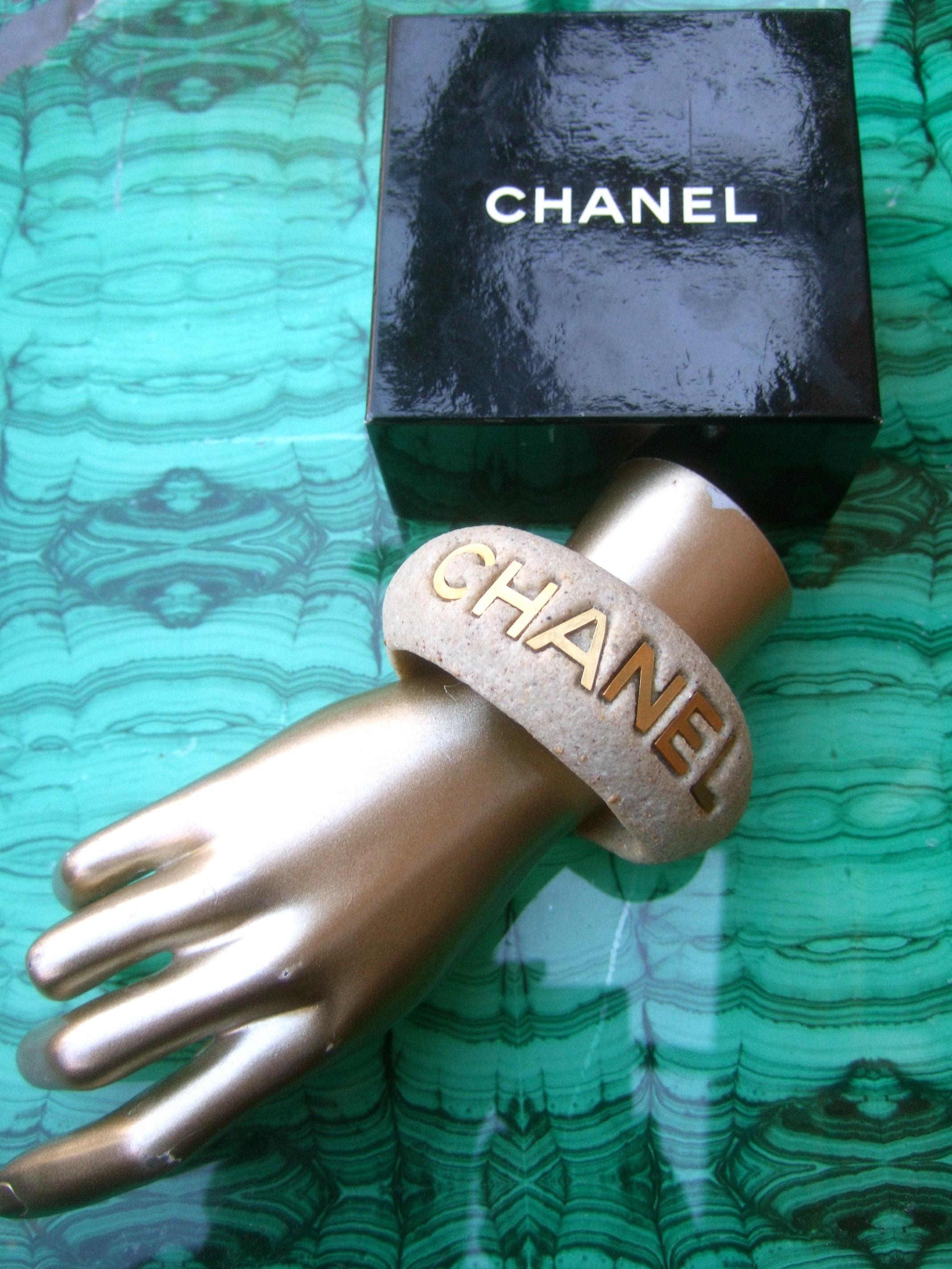 Chanel chic wide molded bisque stone cuff bracelet in Chanel presentation box c 1990s
The stylish Chanel cuff is designed with a textured stone bisque composition that resembles concrete
The bracelet is adorned with the Chanel name on one side in