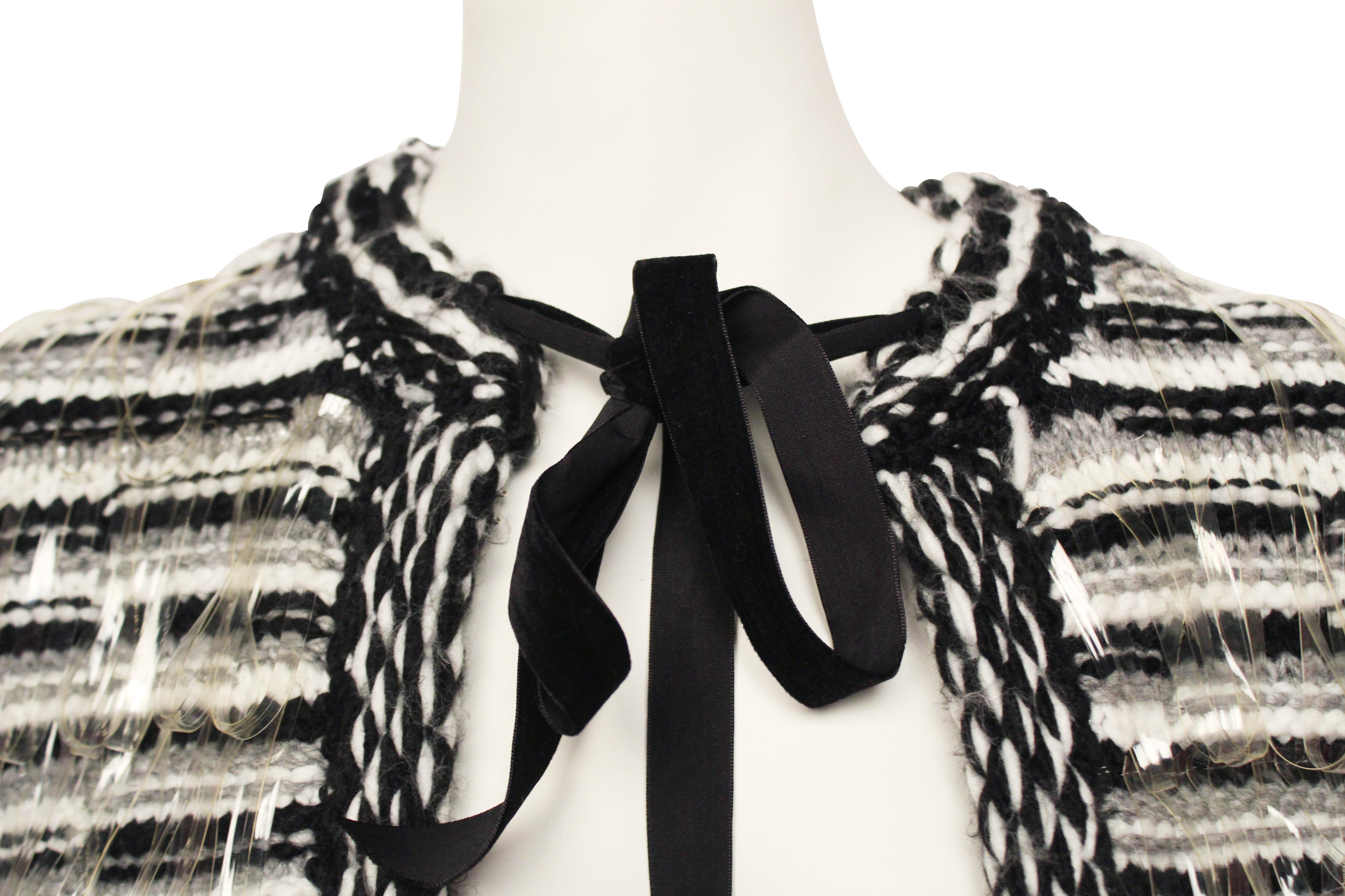 CHANEL black and white woolen cape with plastic loop tabs and velvet ribbon tie. 

Size EU 38.

Made in France.

Serial: P51721V38616
