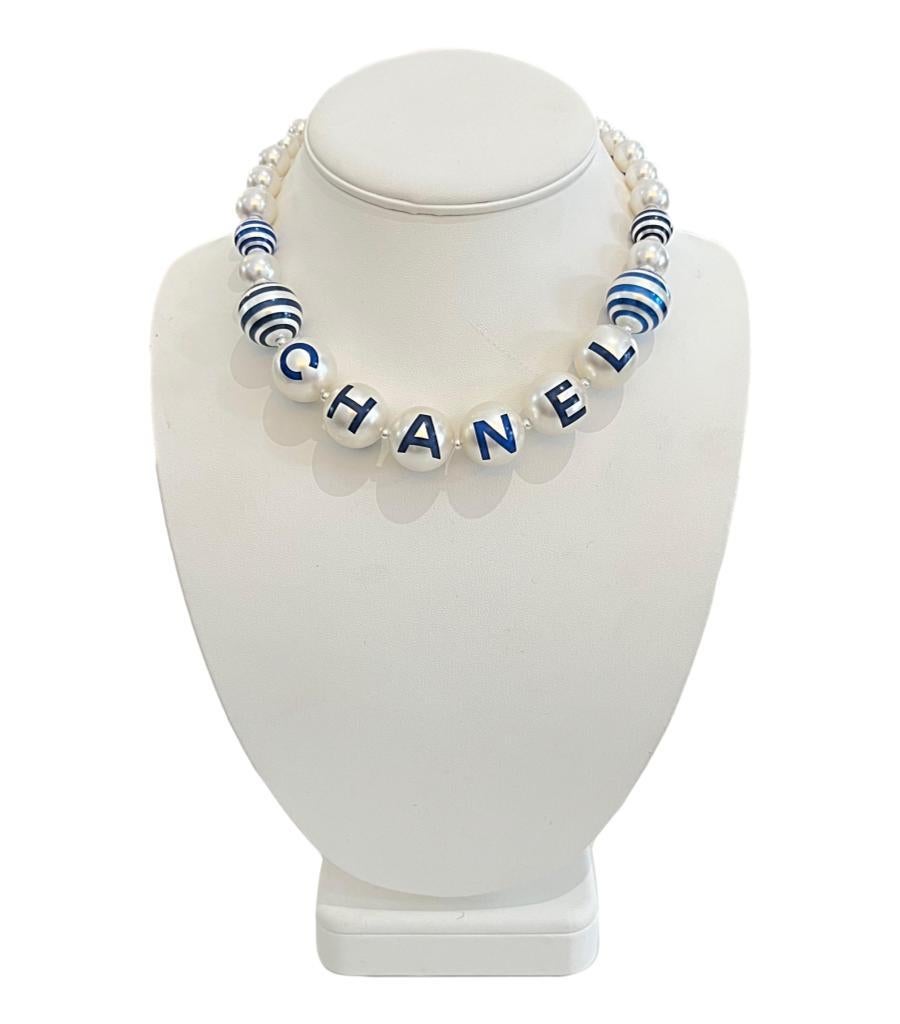 Rare Item - Chanel Worded Pearl Chocker Necklace From 'La Pausa' Collection

Oversized pearls with different shades of blue stripes and having the word 'CHANEL'

printed onto to them. Champagne gold chain to the back of the necklace with a 'CC' logo