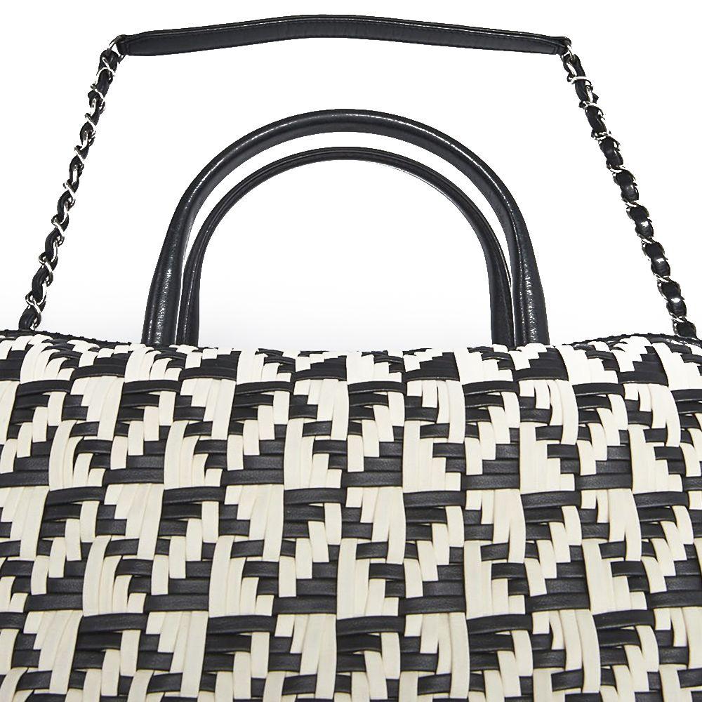 Crafted in Italy from an intricate combination of black and white calfskin leather, this pre-owned bowling bag by Chanel features a distinctive woven exterior, an all-over geometric zig-zag design, and the iconic interlocking CC logo plaque stitched