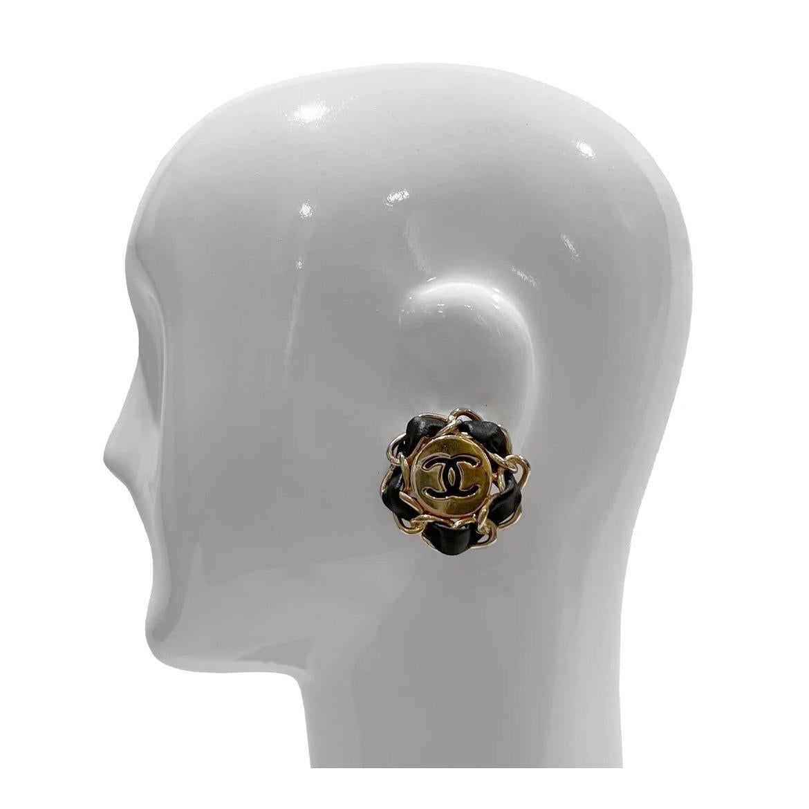 Orecchini a clip in pelle intrecciata di Chanel 
Circa anni '80
Cerchio placcato oro con logo Chanel nero al centro
Bordo intrecciato in pelle nera e catena dorata
Prodotto in Francia
Condizioni: Eccellenti condizioni vintage. Alcuni piccoli graffi