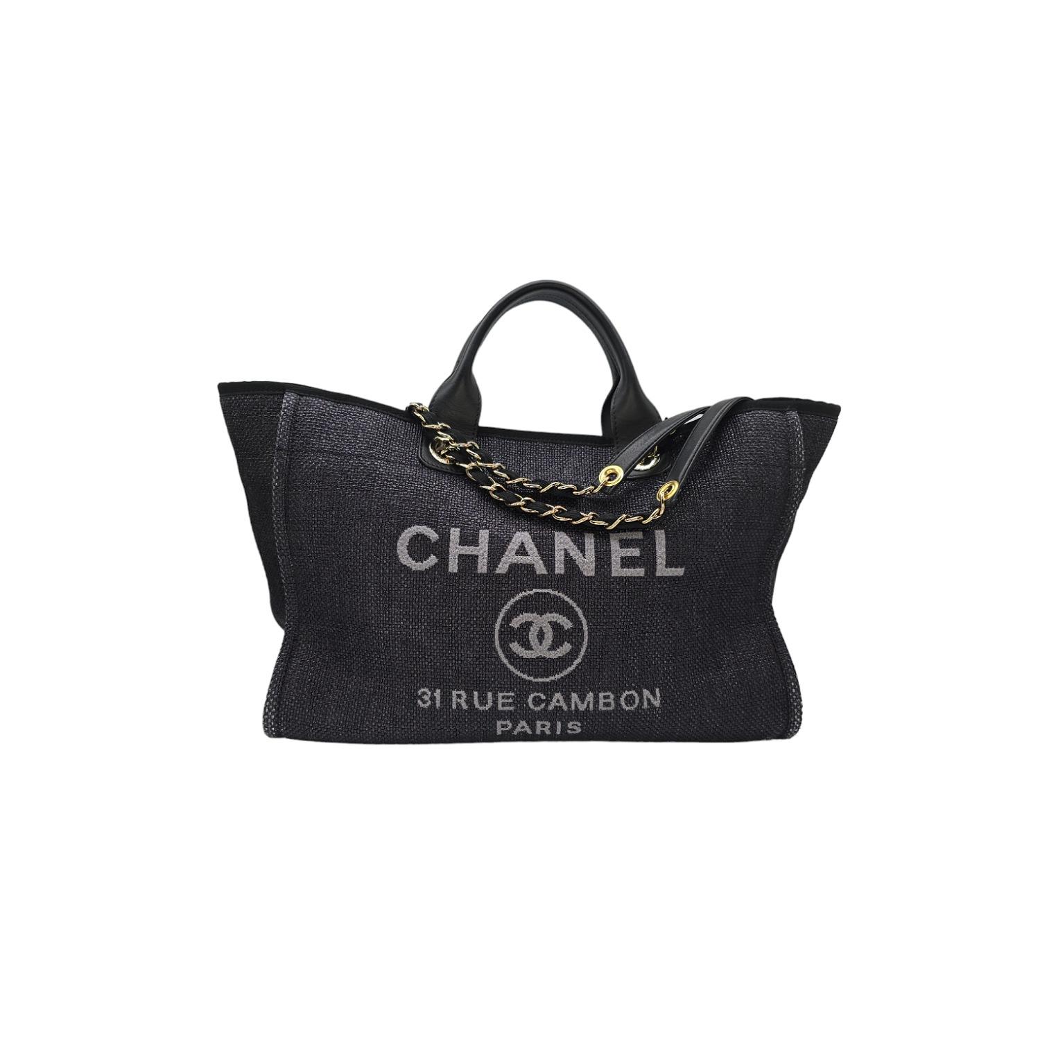 Crafted from fine woven straw raffia, this Chanel Deauville tote boasts a black and gray embroidered Rue Cambon Paris logo on the front. Equipped with leather top handles and a fabric threaded gold chain shoulder strap, it offers functionality with