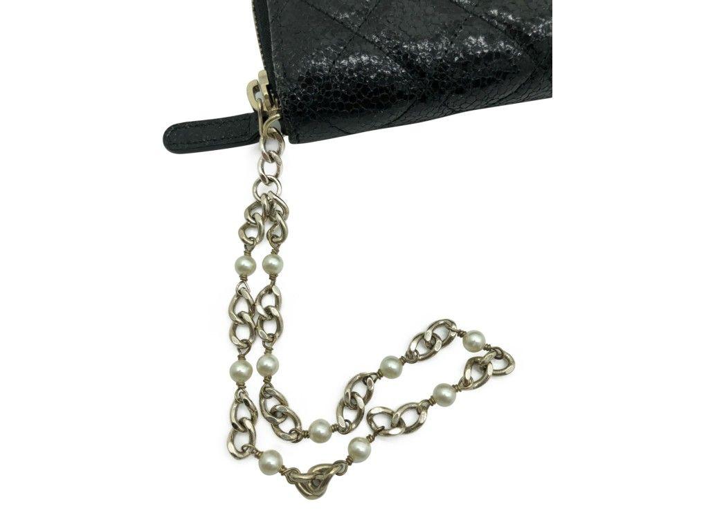 This stylish Chanel Clutch/Wallet is crafted of luxurious calfskin leather in black with a diamond quilt and a crackled luster. The wallet features a small pearl lined gold CC logo and a gold chain and pearl wristlet. This wallet is in as new