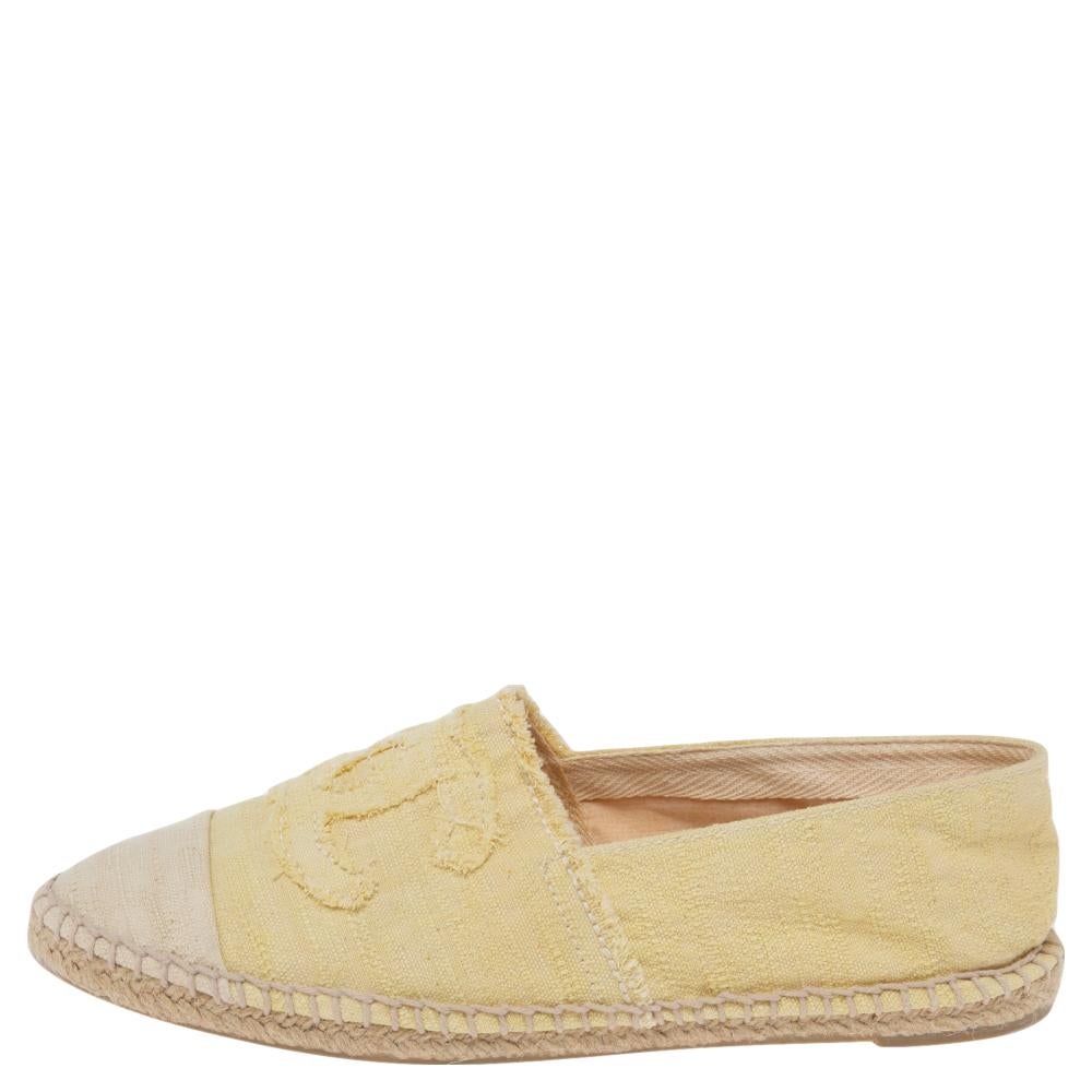 This pair of yellow and beige Chanel canvas espadrilles flats come with a distinctive raw-edge trim. Structured with cap-toes, it features the iconic interlocking CC logo on the vamps. A fine stitch detailing enhances the look while a jute braid at