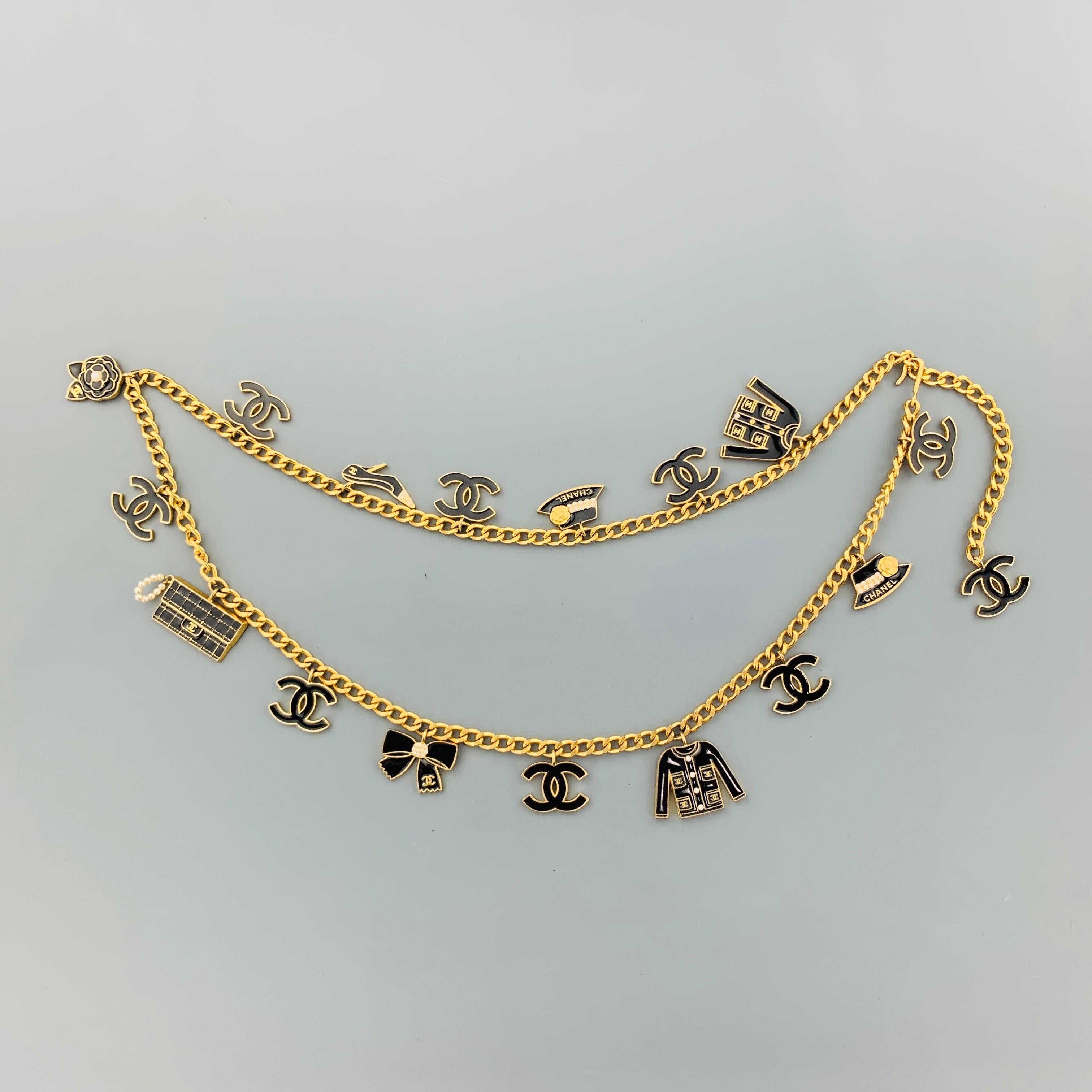 CHANEL Fall Winter 2002 Collection belt comes in bold yellow gold tone metal and features a chain belt strap adorned with black enamel, faux pearl embellished Coco Chanel charms in jacket, CC logo,  hat, pump, camellia, purse, and bow motifs. Wear