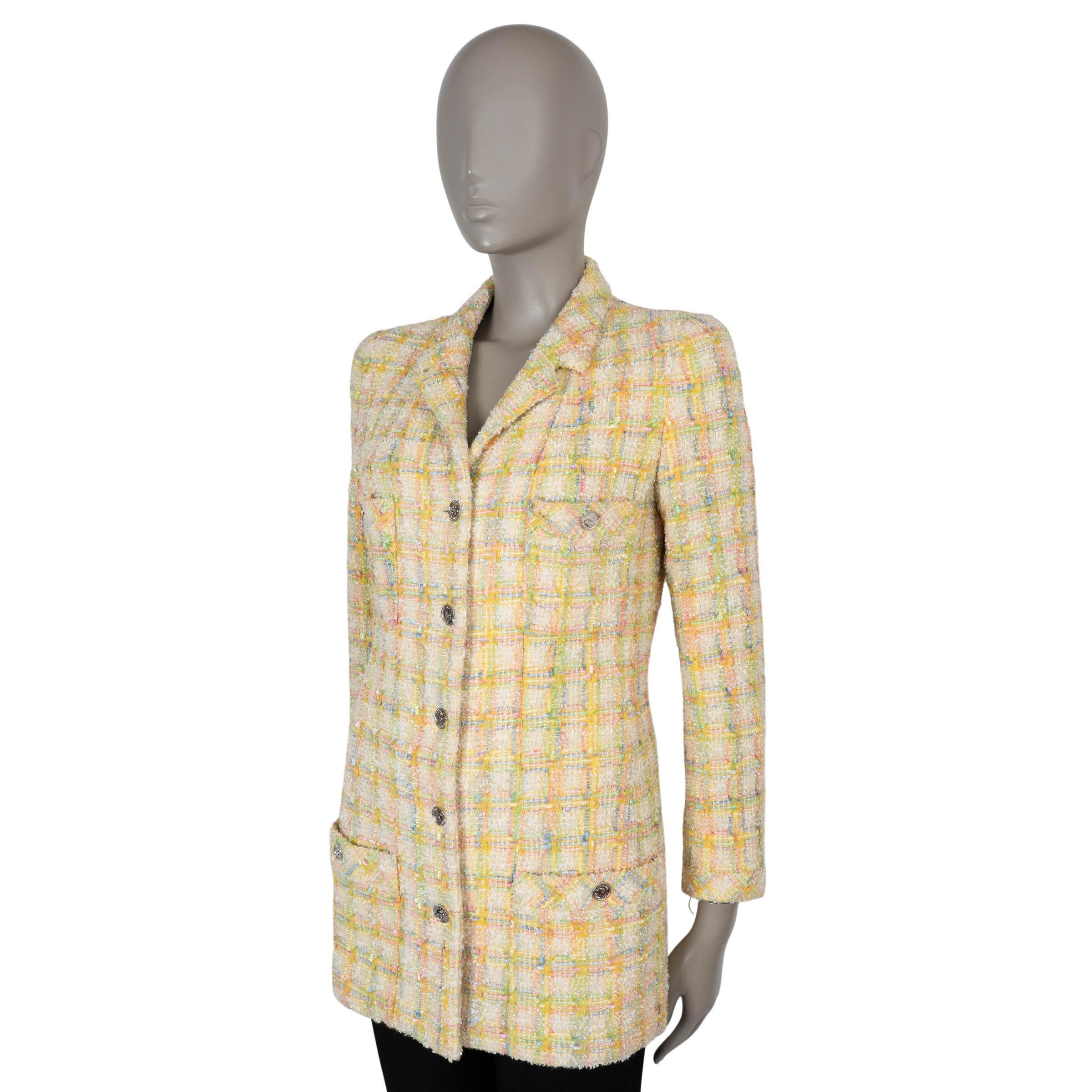 Questa giacca Chanel autentica al 100% è realizzata in tweed beige a frange di nylon (50%) e lana (50%) con un vivace plaid di giallo, verde, blu e rosa. Presenta una silhouette raffinata e aderente con una lunghezza maggiore, revers corti e