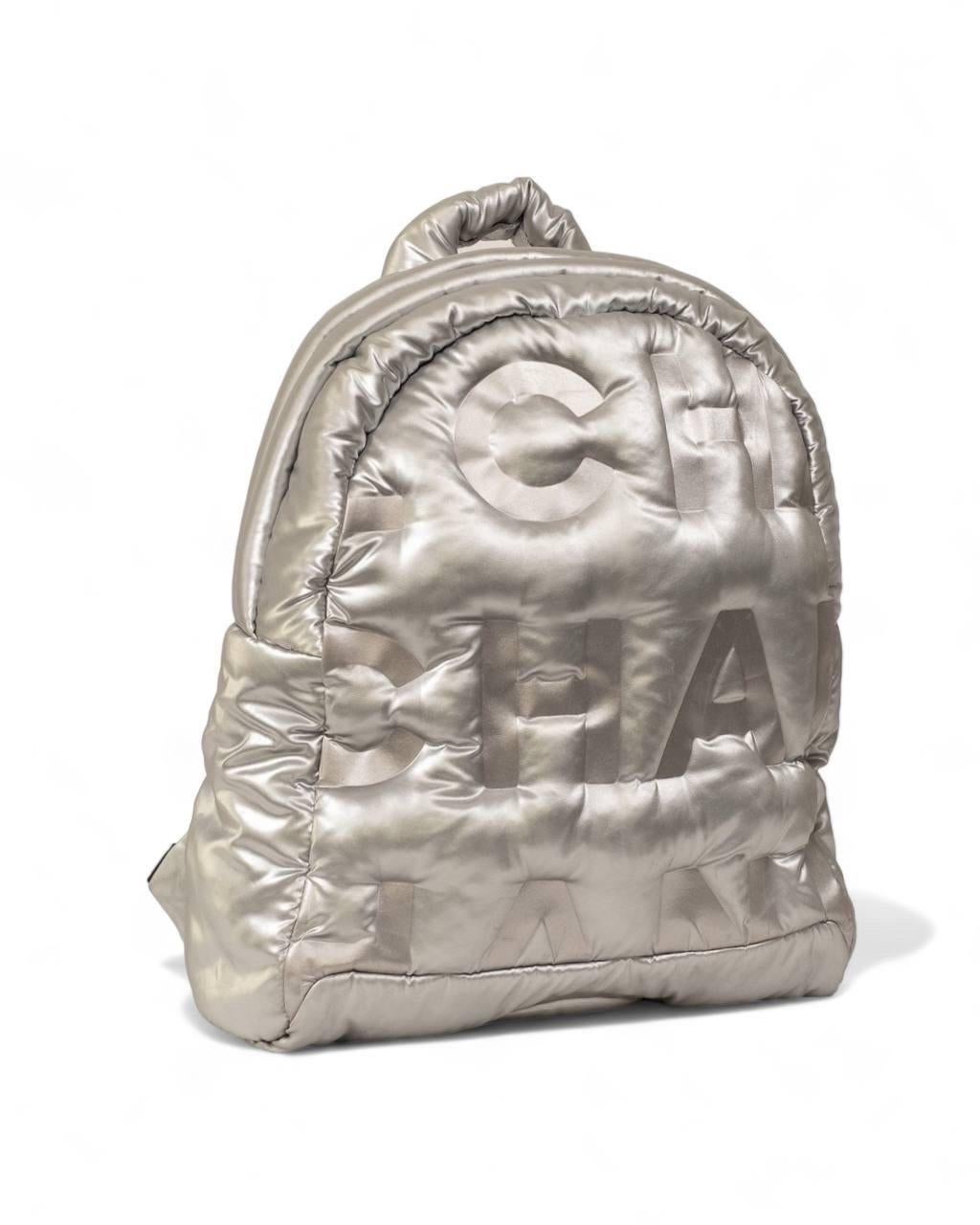 Zaino firmato Chanel, modello Doudone, realizzato in nylon colore argento con rifiniture in tessuto nero e hardware argentati. Doté d'une fermeture à glissière double, il est réalisé en nylon Nero, très résistant. Munito di doppia tracolla imbottita