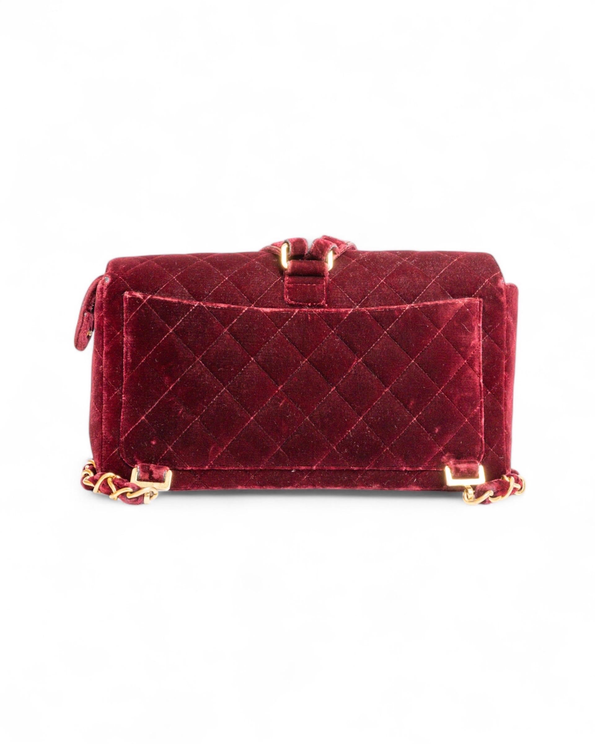 Zaino firmato Chanel, realizzata in velluto bordeaux con hardware dorati. Dotata di una patta con chiusura a girello e logo CC e una zip. internamente rivestito in pelle liscia bordeaux, abbastanza capiente. Munito di due spallacci in velluto e