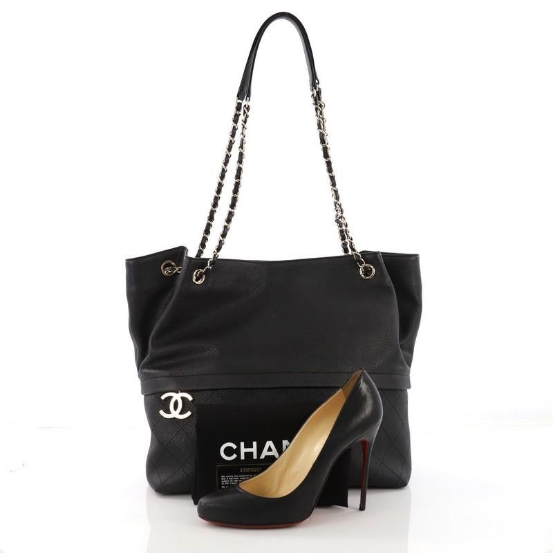 This Chanel Zip and Carry Shopping Tote Quilted Caviar Large, crafted from black quilted caviar leather, features woven-in leather chain straps with leather pads, exterior zip pocket, and gold-tone hardware. It opens to a black fabric interior with