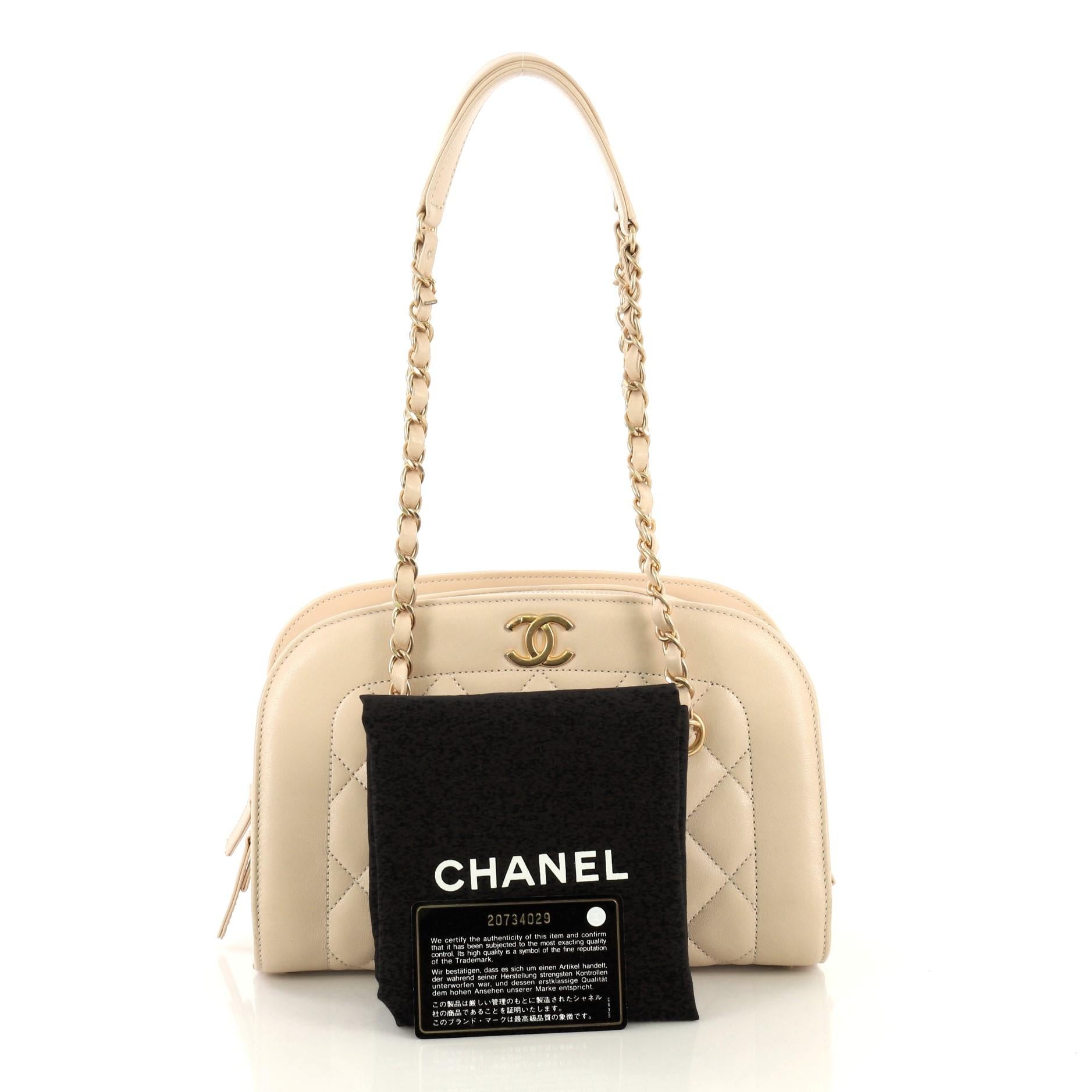 This Chanel Zip Around Chain Camera Bag Quilted Lambskin Medium, crafted in neutral leather, features woven-in leather chain straps with leather pad, CC logo at front and matte gold-tone hardware. Its zip-around closure opens to a red leather
