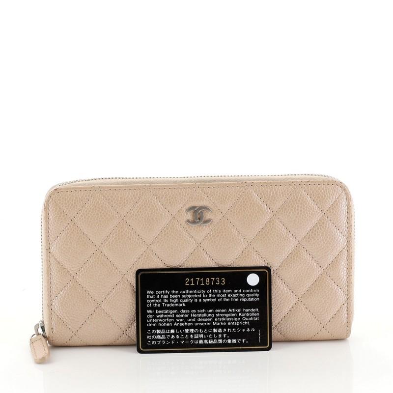 This Chanel Zip Around Wallet Quilted Caviar Long, crafted from pink iridescent quilted caviar leather, features CC interlocking logo and silver-tone hardware. Its zip-around closure opens to a pink leather and fabric interior with multiple card