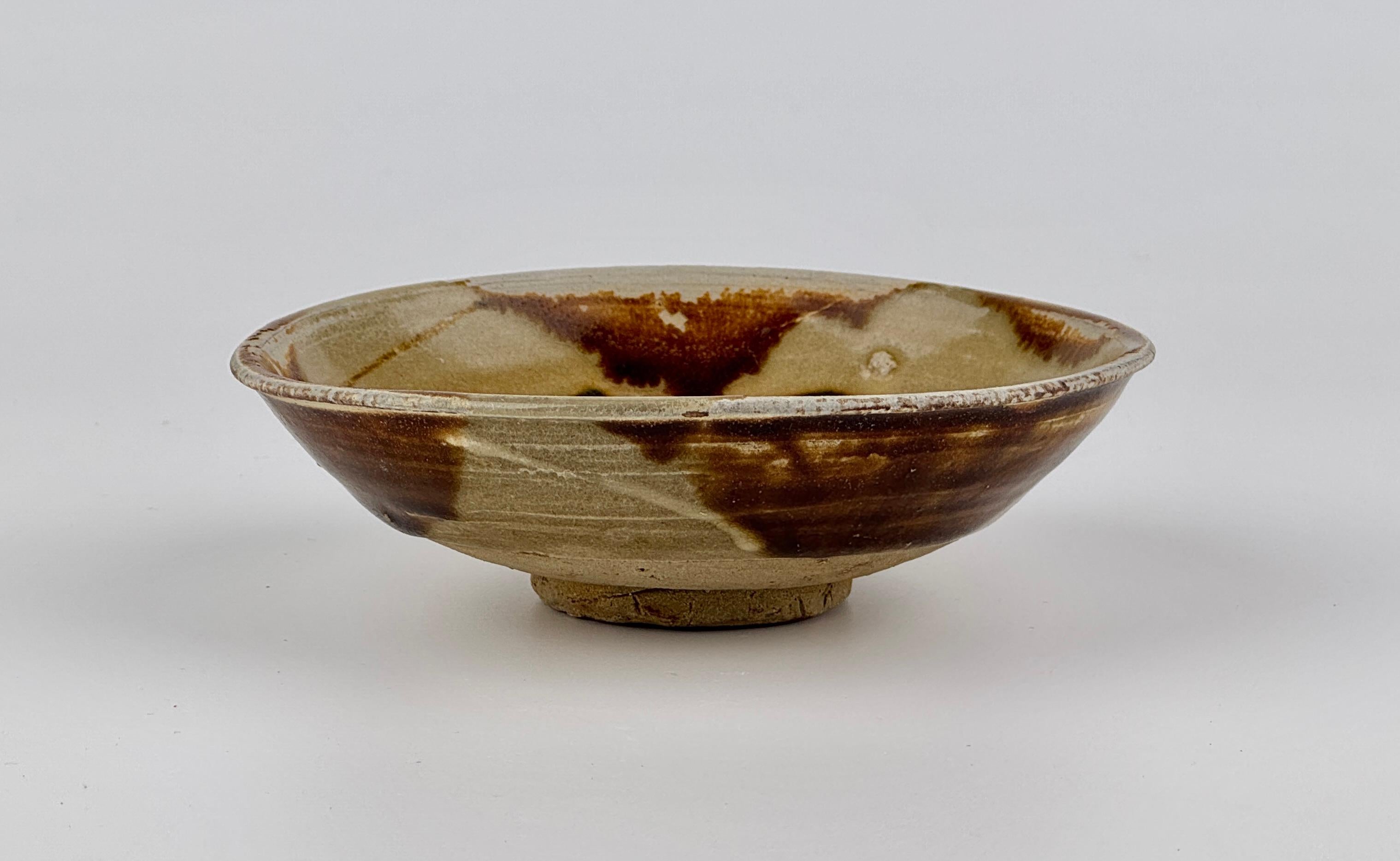 The edges have been dipped in four places with brown, probably iron-oxide. The well of the bowl is freely painted in deep green and coffee coloured brown. These are characteristic features of Changsha ware. The Asian Civilisations Museum in